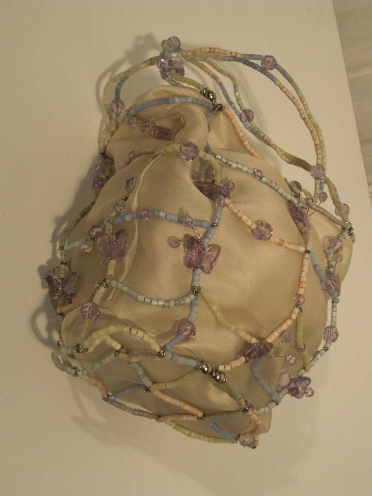 An adorable Bottega Veneta evening bag made of ecru silk organza pouch surrounded by a delicate glass bead and wire basket in pastels.