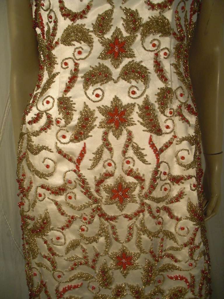 A great 1960s silk satin fitted sheath dress heavily beaded all over in stylized florals and gold and burnt orange beads. Fully lined. Zipper at back center.
