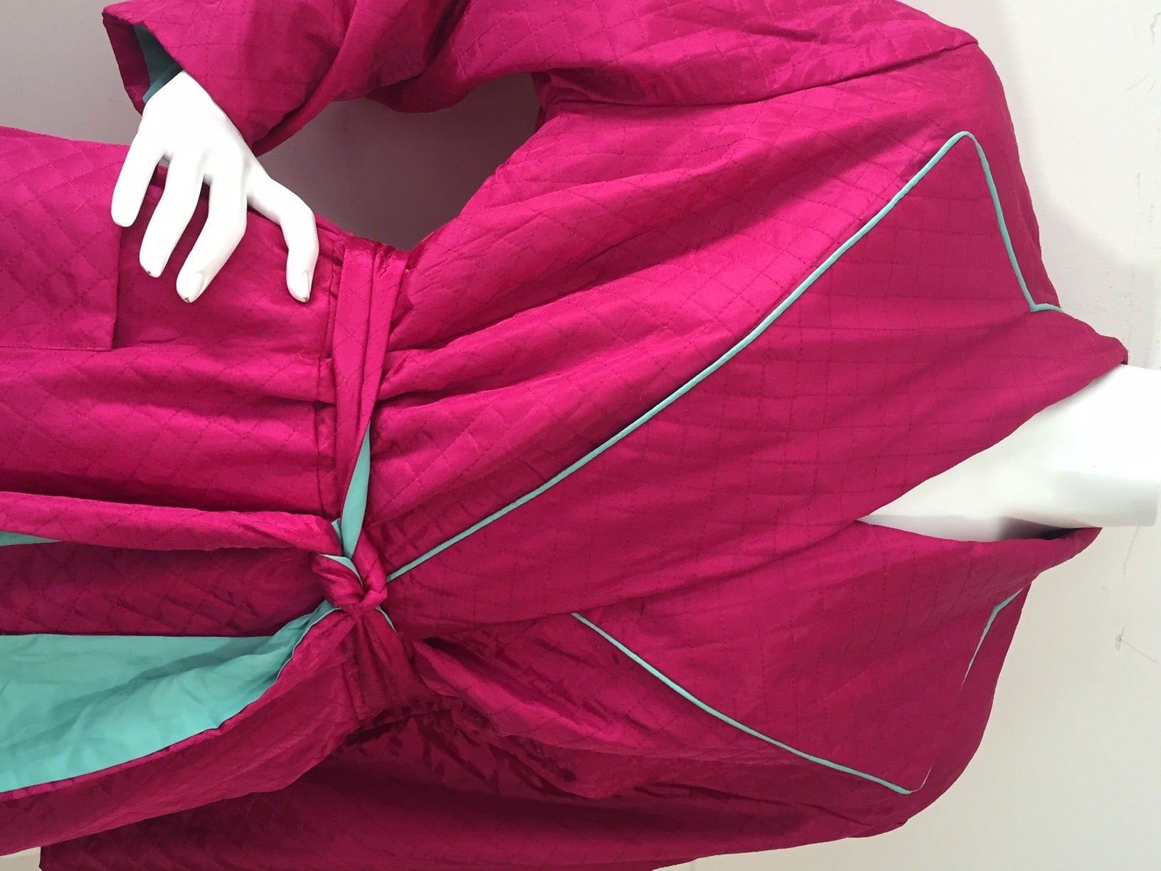 A fabulous never-worn 1950s quilted fuchsia satin acetate dressing gown/robe with mint green piping and lining.  Attached belt.  Patch pocket. Inner tie closure with snap at front waist. Perfect condition.