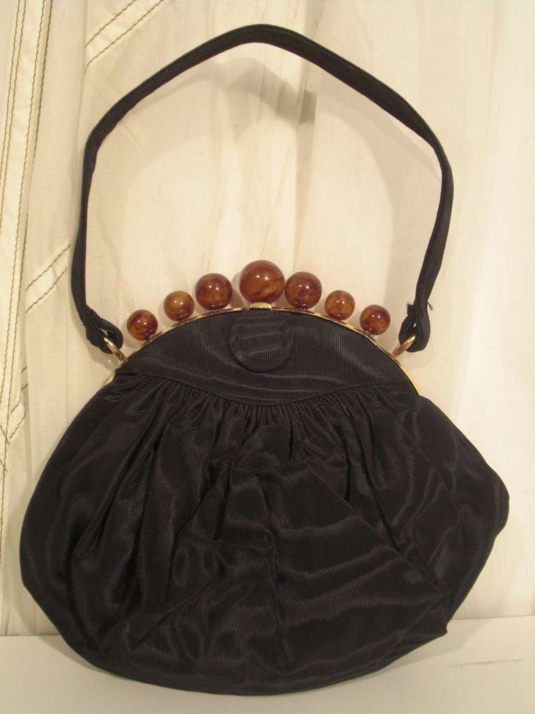 A beautiful 1940s Koret silk moire evening bag with a short handle, a curved clasp frame and a row of crown-like faux amber beads along top of frame.  Attached coin purse and original mirror included.