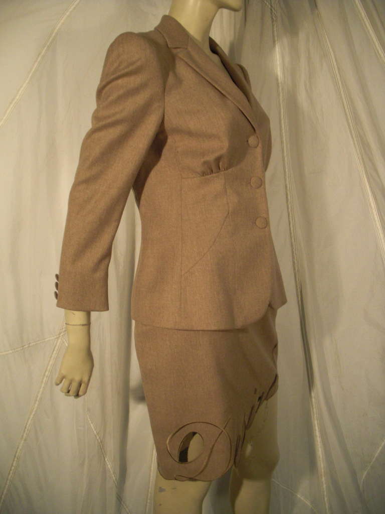 A fabulous Moschino couture statement skirt suit in heathered camel wool.  Jacket has vintage styling including gathers under the bust and covered buttons. Skirt is asymmetrical and has the word 