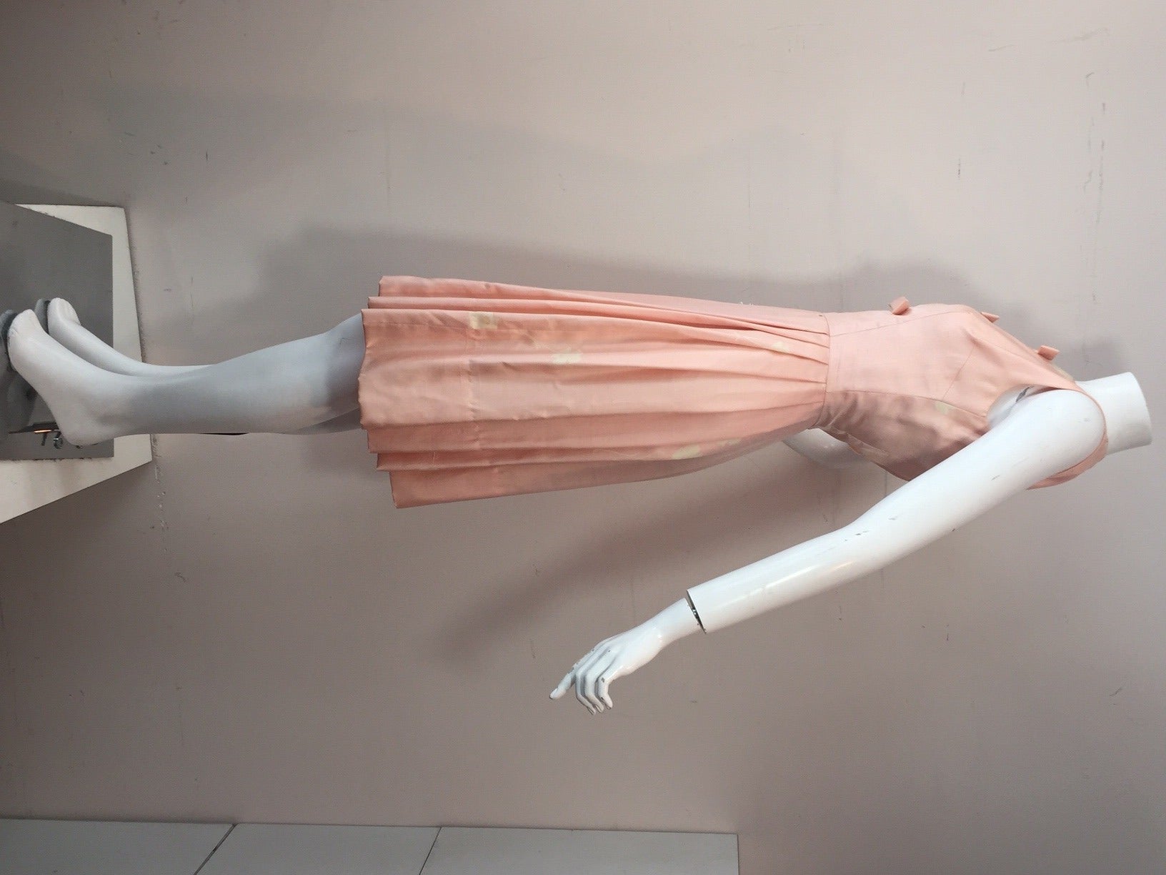 A sweet 1950s pink and white printed silk sleeveless dress:  Dirndl-style skirt pleating with 3 bows down center front.  zippered back (too small for mannequin).  Original matching fabric stole included.