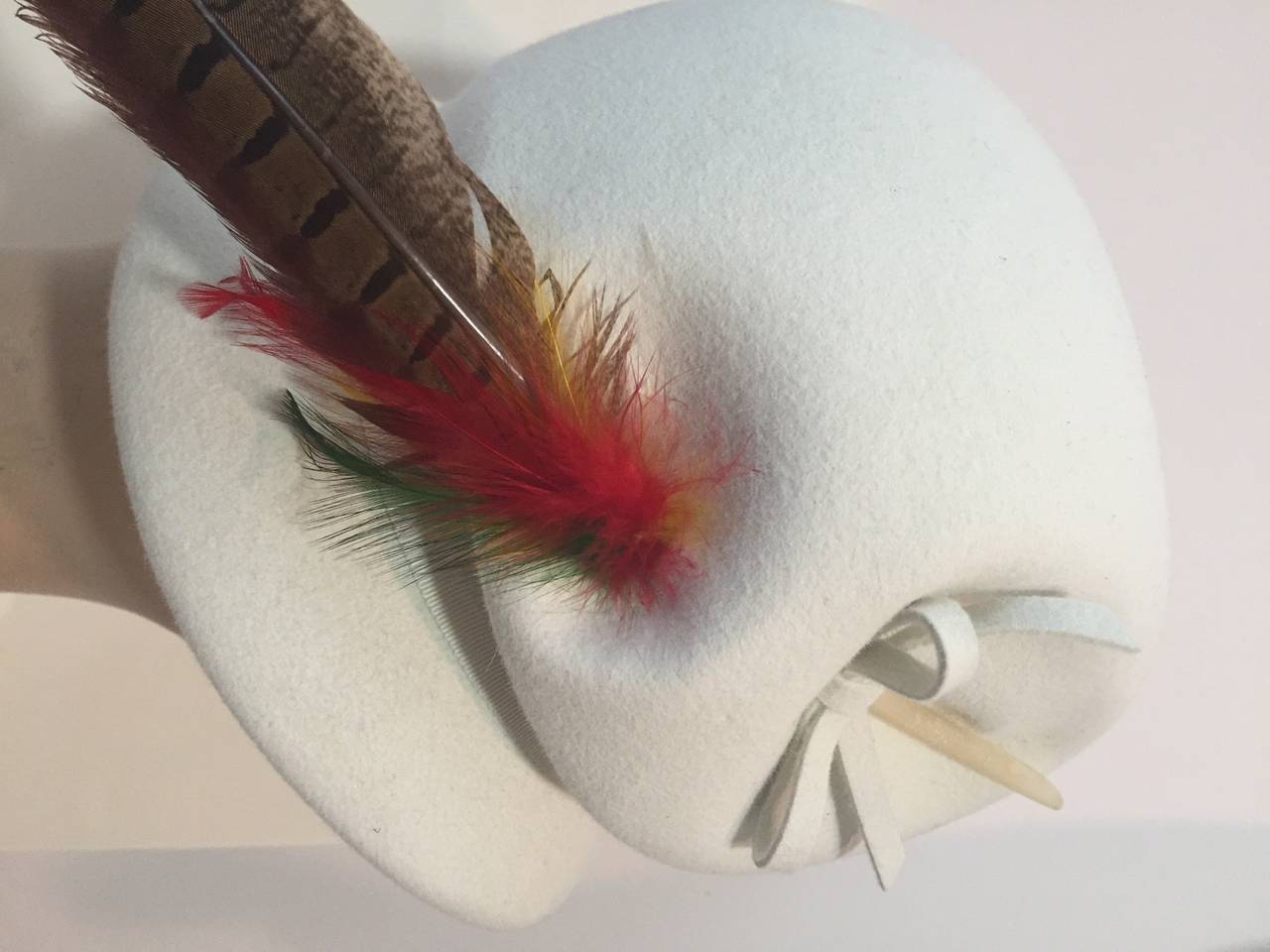 A fabulous 1960s Mod hat by Valerie Modes in winter white wool felt:  in EXCELLENT condition.  Grosgrain band on outside and inside.  Long dramatic pheasant feather spray makes this a jaunty delight!