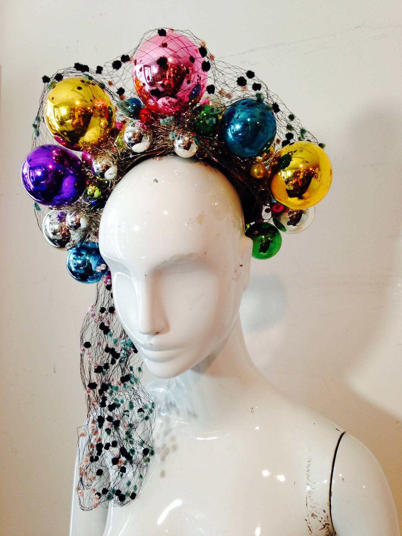Be the hit of the party with this 1940s holiday hat!  From divine San Francisco milliner extraordinaire Irina Roublon comes this festive extravaganza of glass christmas ball ornaments, lame, tinsel and veiling. Combs attach this so it stands up like