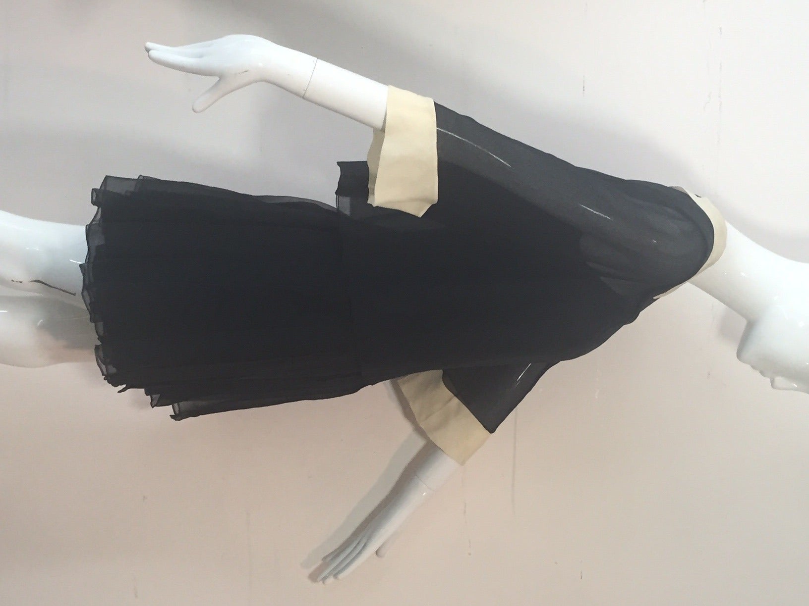 A super-cute 1960s James Galanos 2-piece black silk chiffon mini dress:  dress has spaghetti straps, boned structured bodice, heavily pleated, multiple layered, dropped waist skirt.  Chiffon overlay jacket buttons up the back and features bone