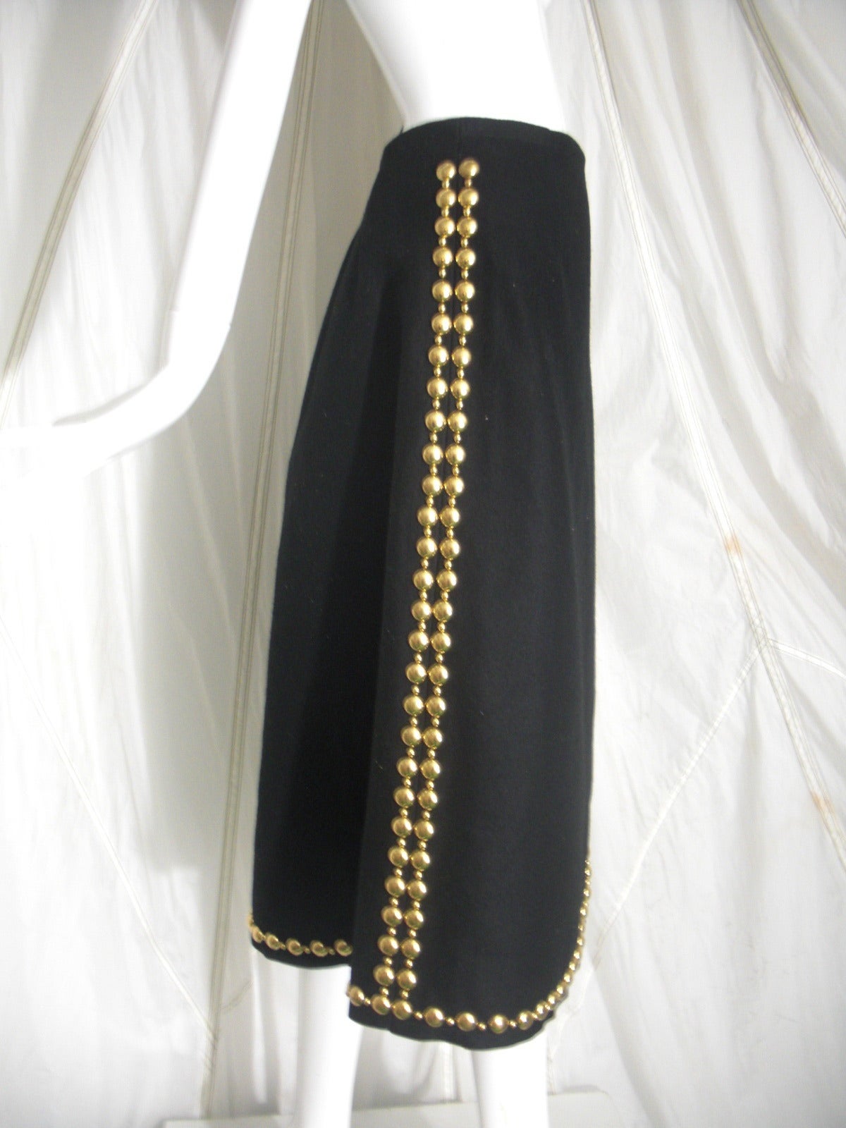A smart, unlined 1970s Adolfo wool felt wrap skirt with no waistband.  Curved front hem is completely edged in large gold studs.