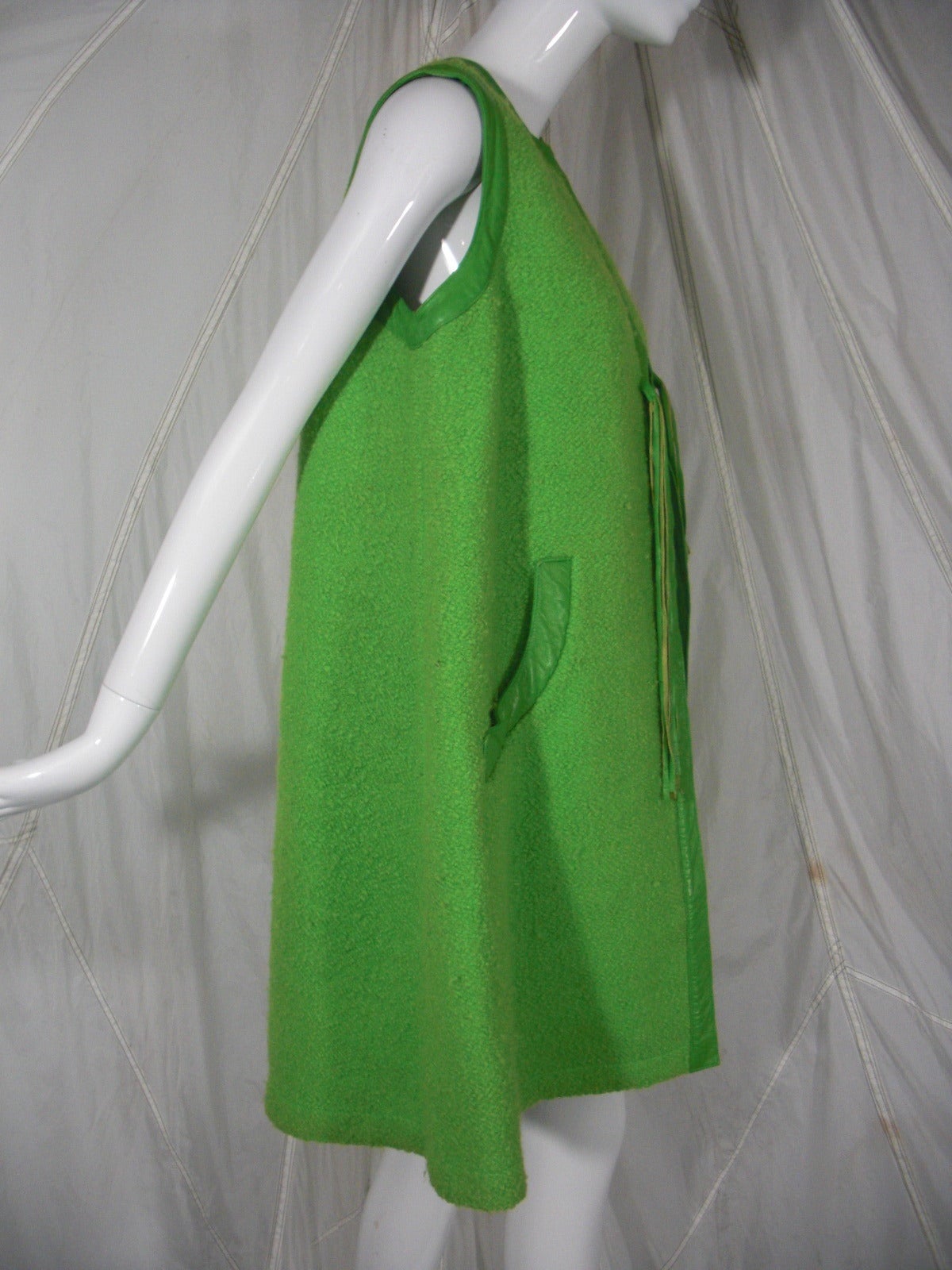 A mod 1960s Bonnie Cashin apple green wool vest with front closure and leather trim at armholes and neckline.  Trimmed side pockets and tie closure.