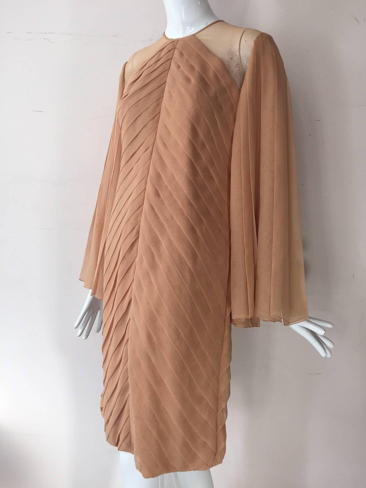 1980s James Galanos peach blush silk chiffon pleated cocktail dress with heavily pleated fan-sleeves.  Hand rolled hem on sleeves. Body constructed with 4 layers of silk chiffon. Completely lined. Original hem.  Back gold-tone buttons. 