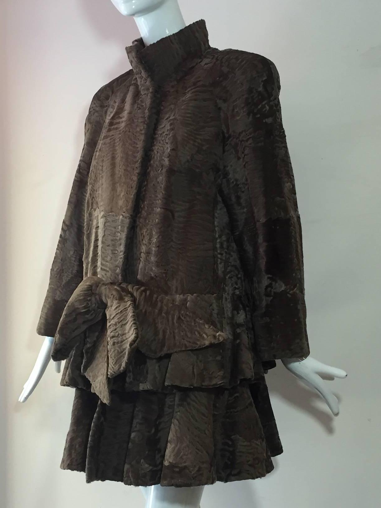 A gorgeous 1980s James Galanos taupe swakara lamb coat:  Raglan sleeves with padded shoulders and banded collar.  Dropped waist styling, a la 1920s, with tiers of flared panels and front bow.  Slight swing shape to back panel. Bergdorf Goodman. 