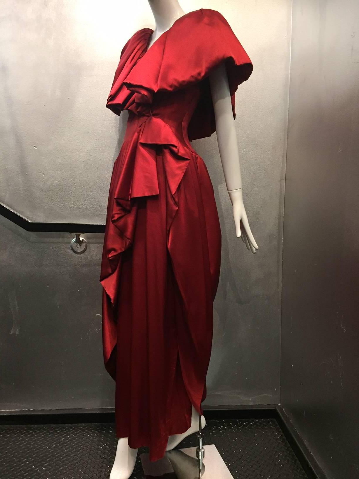 1980s British couture scarlet silk satin ruffled neckline and hem evening gown: fitted and shaped waist and bodice are trimmed with extravagant ruffles at neckline.  Heavily gathered skirt with underskirt. Ruffles and overskirt are faced with