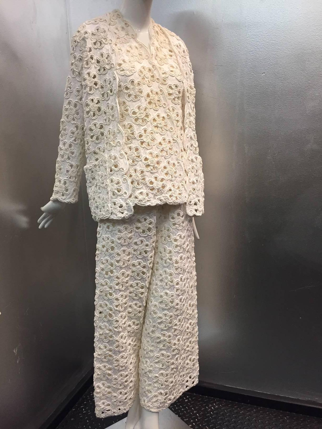 A fabulous 1960s James Galanos Mod style cream embroidered lace 3-piece pant suit.  Tunic top is lined in silk chiffon with a wrap-style snap closure, wide-leg pants with 