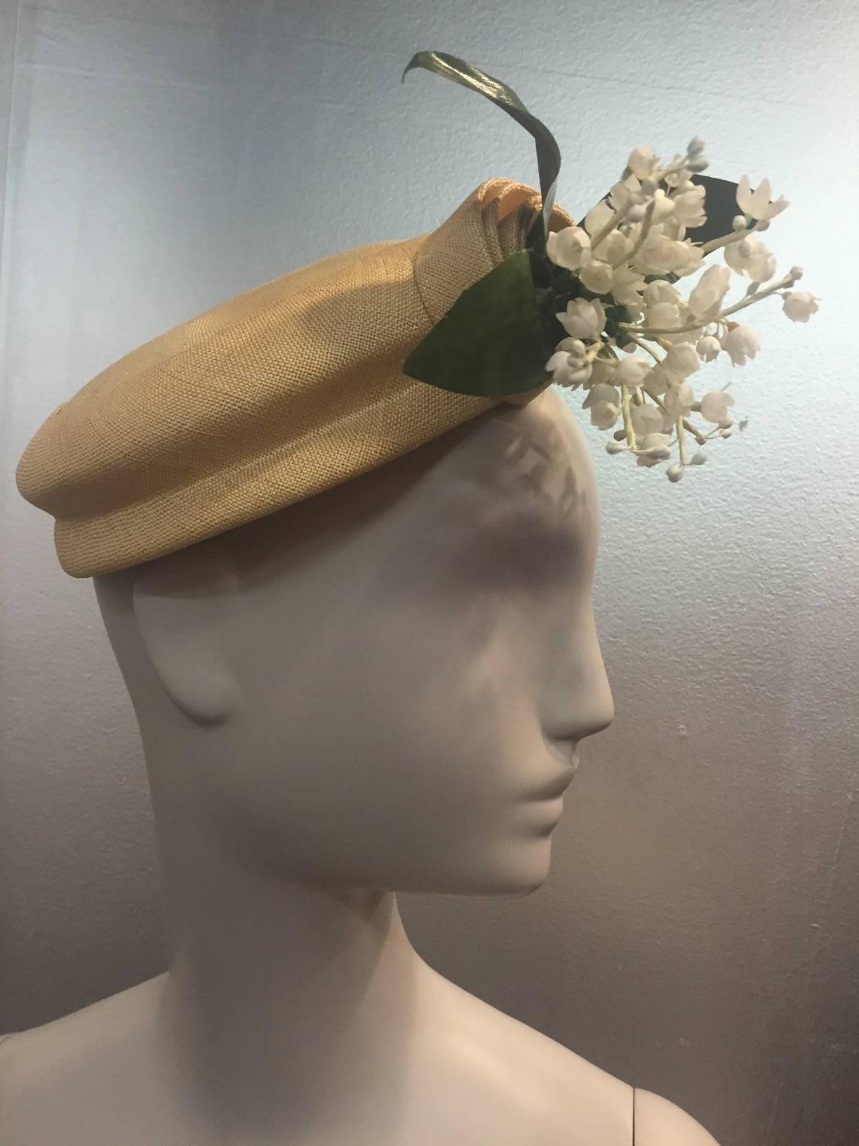 A gorgeous 1950s Emme - New York natural straw hat with spiral straw embellishment and lily of the valley spray at front.  Inside combs keep hat securely attached to crown of hair style. 