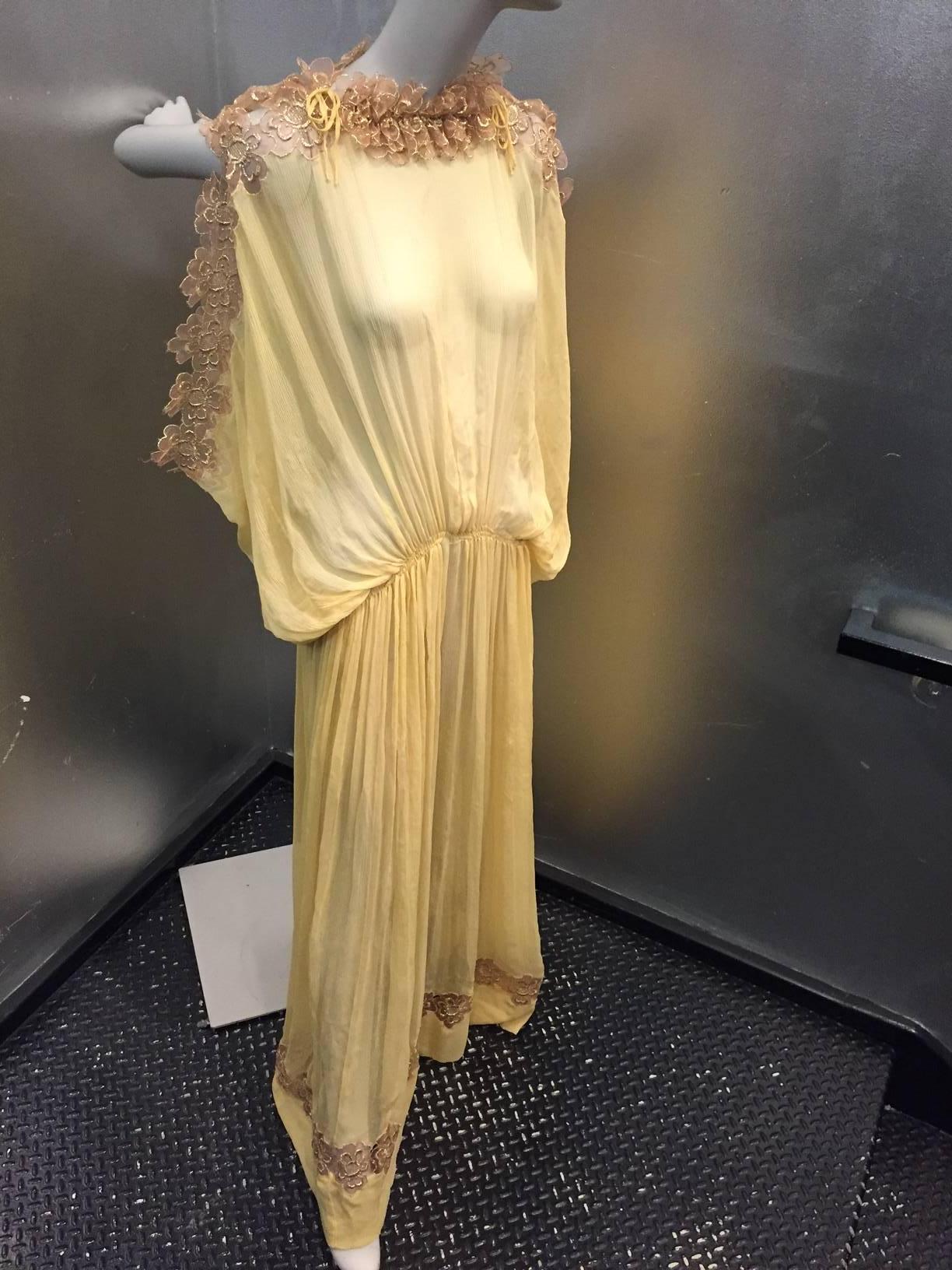 A gorgeous 1970s Gunn Trigeré honey-color crinkled silk chiffon Goddess gown w/ lamé floral lace trim at neckline and shoulders.  Gathered, dropped waist for a "Delphos" look.  Hem is trimmed in lamé lace also. 