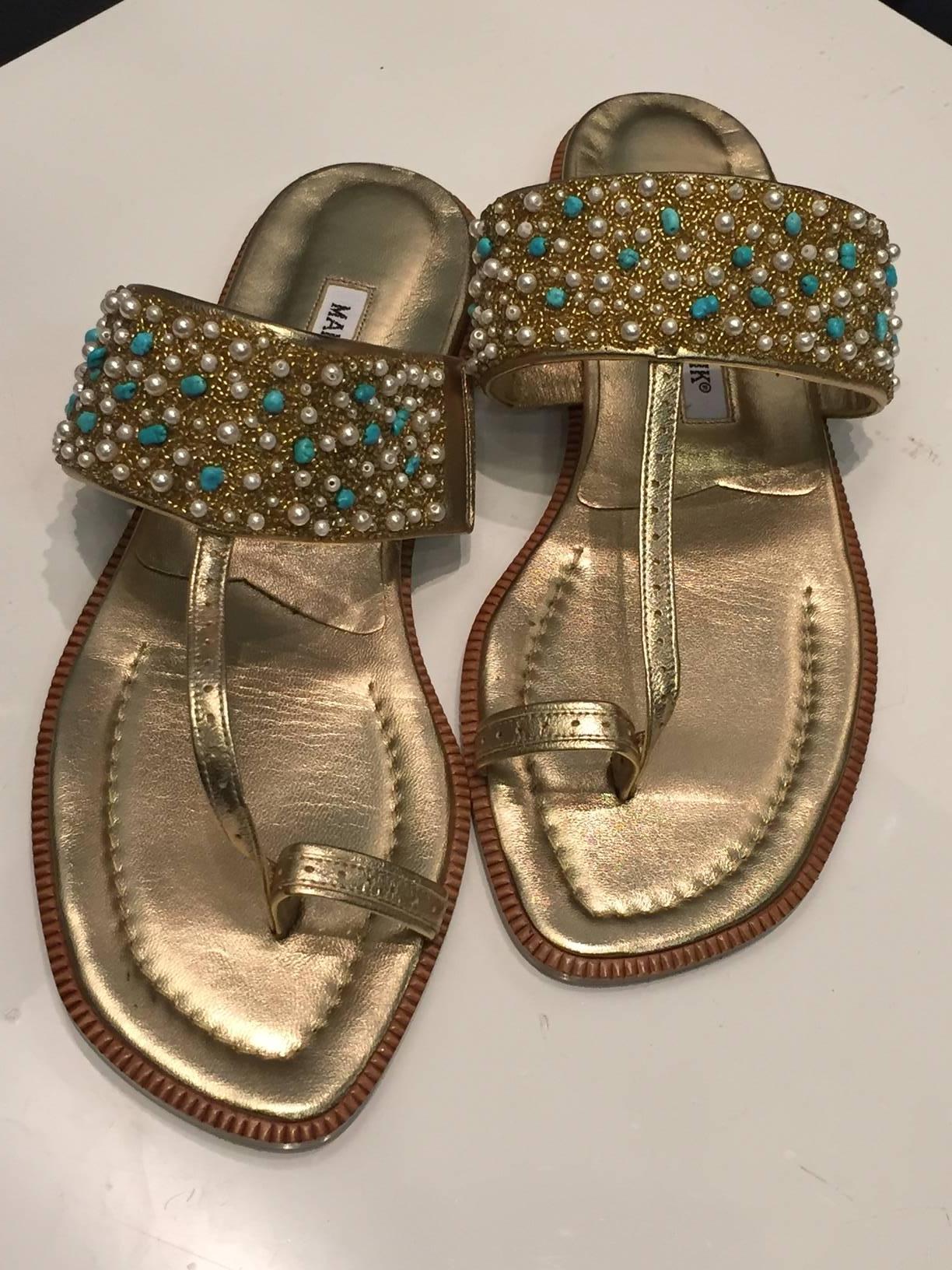 A classic Manolo Blahnik gold leather sandal with turquoise, pearl and gold beaded band at vamp and loop toe. 

Size 37