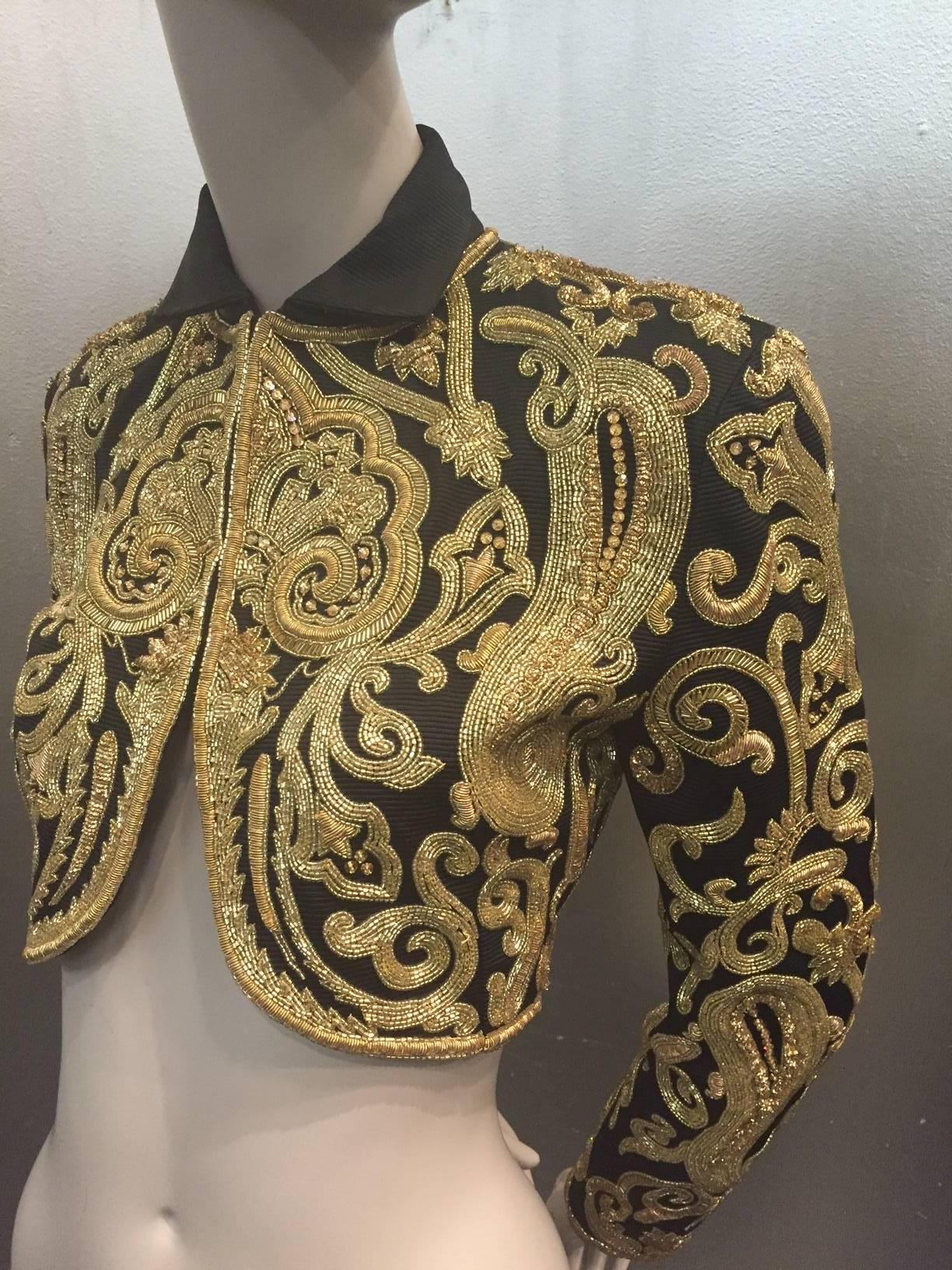 A fabulous 1980s Genny for Panache cropped Toreador jacket in black silk faille entirely encrusted in a paisley pattern with gold braid, rhinestones and beadwork.  Rounded bottom hem and small collar. 3 hook and eye closures. 