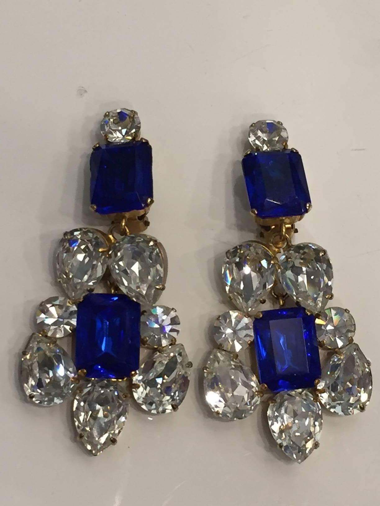 A vibrantly cut statement-sized pair of drop chandelier earrings. Featuring square cut Sapphires as well as pear and round cut clear rhinestones in a prong setting. Stunning and elegant vintage earrings from the 80's. 