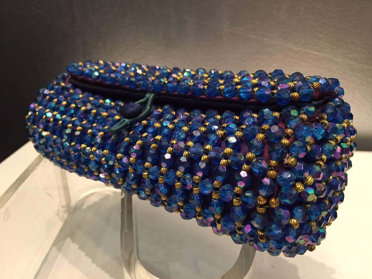 A gorgeous 1950s Koret sapphire blue and gold beaded barrel clutch with silk satin lining. Loop and button closure. Beading is acrylic with brass spacer beads. 