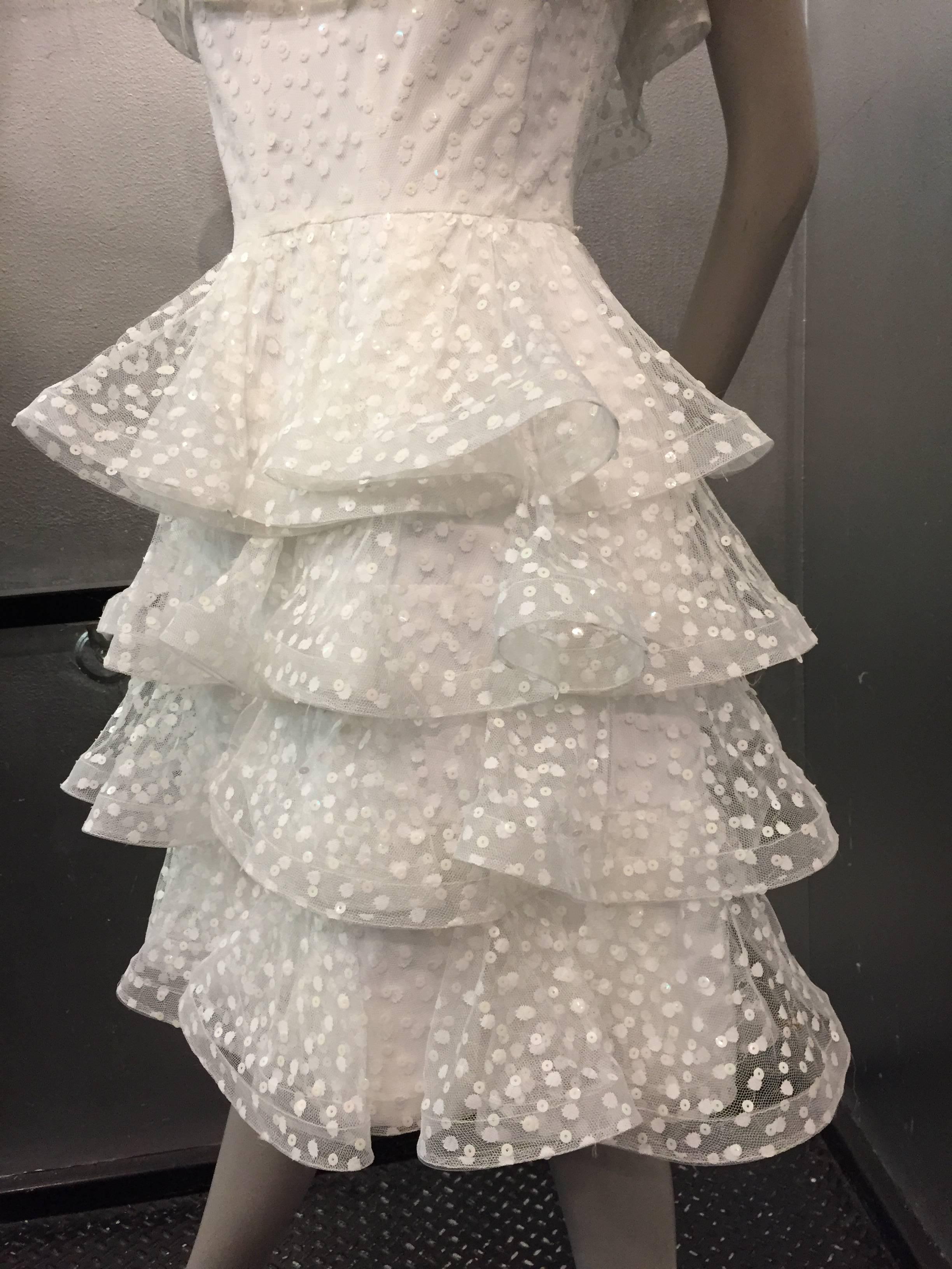 A sweet 1980s Arnold Scaasi tiered white ruffled cocktail dress in sequin embellished pointe d'esprit! Layers of ruffles at the off-the-shoulder neckline and tiers of ruffles in the skirt. 