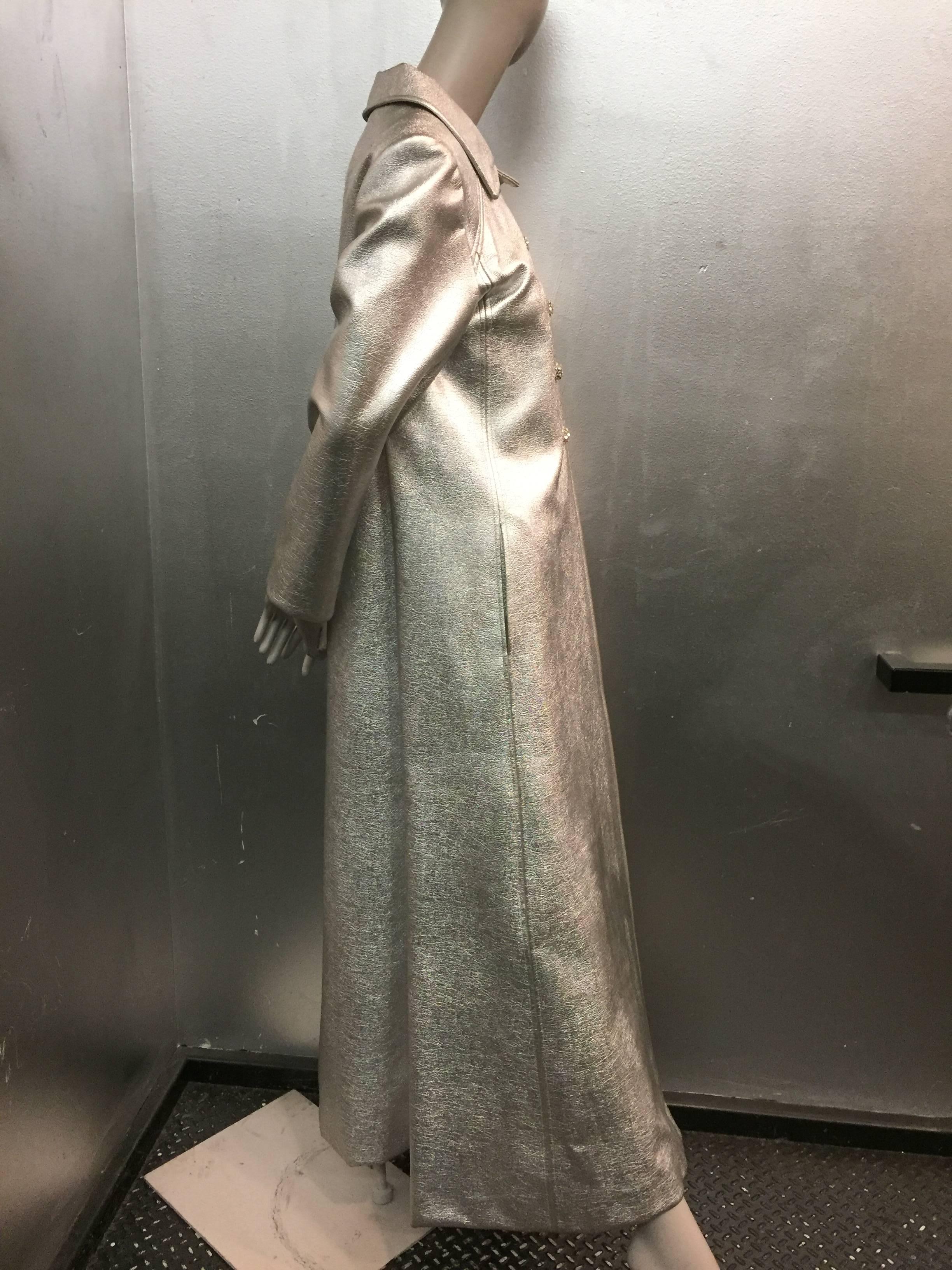 A fabulous 1960s Saks Fifth Avenue silver vinyl maxi coat with a back belt and rhinestone buttons. Be the holiday stand out in this never-worn mint condition evening coat. 