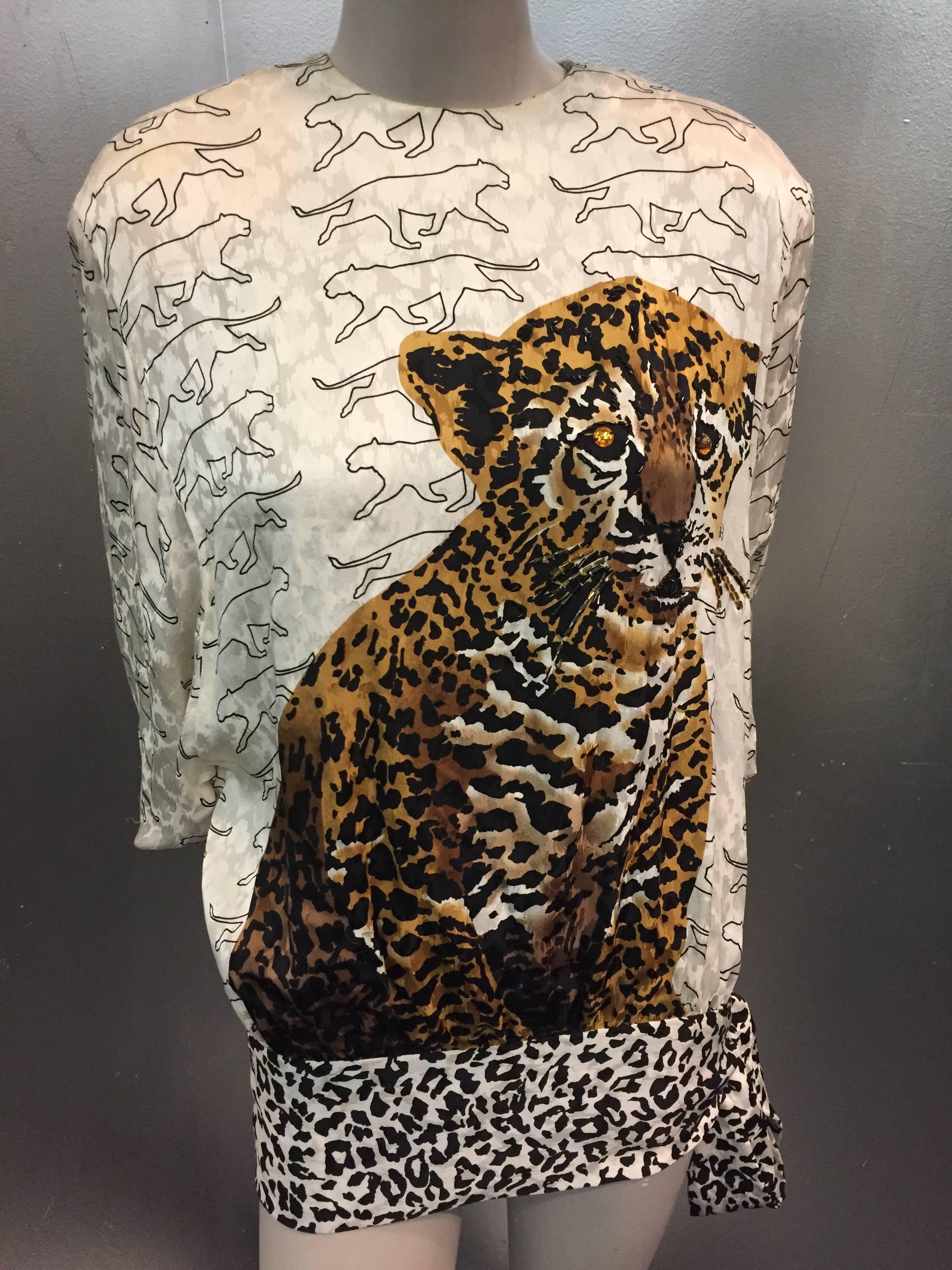 A splashy 1980s Julie Francis dolman sleeved silk blouse in a leopard silhouette print with a large baby leopard print in front.  Black and white leopard print silk hip sash at hem.  Shoulder pads and back buttons. 