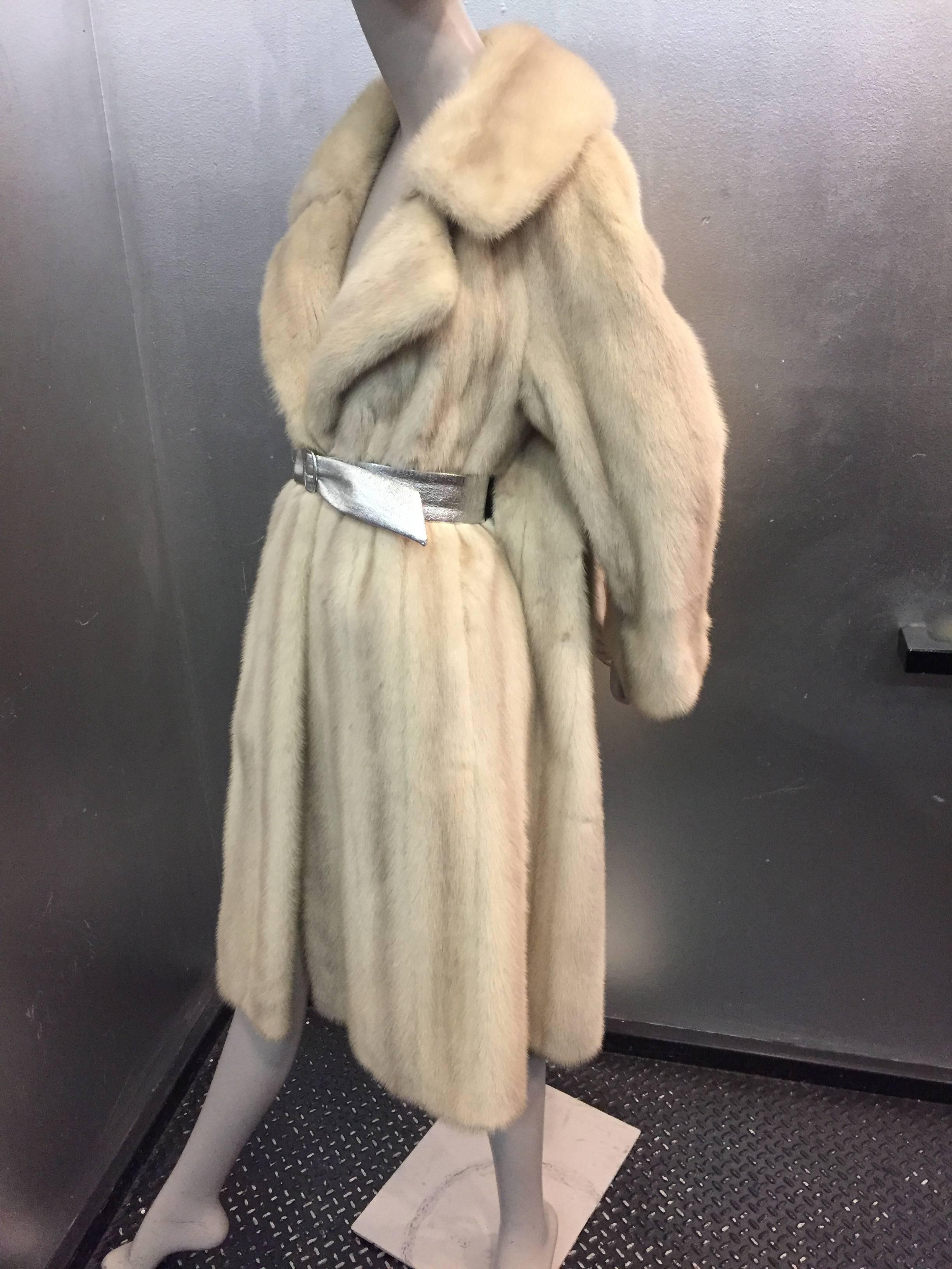 A luxurious Tourmaline mink stroller features large notched collar and self belt construction it is featured here with a silver vinyl belt a great accent to this natural pelted beauty!