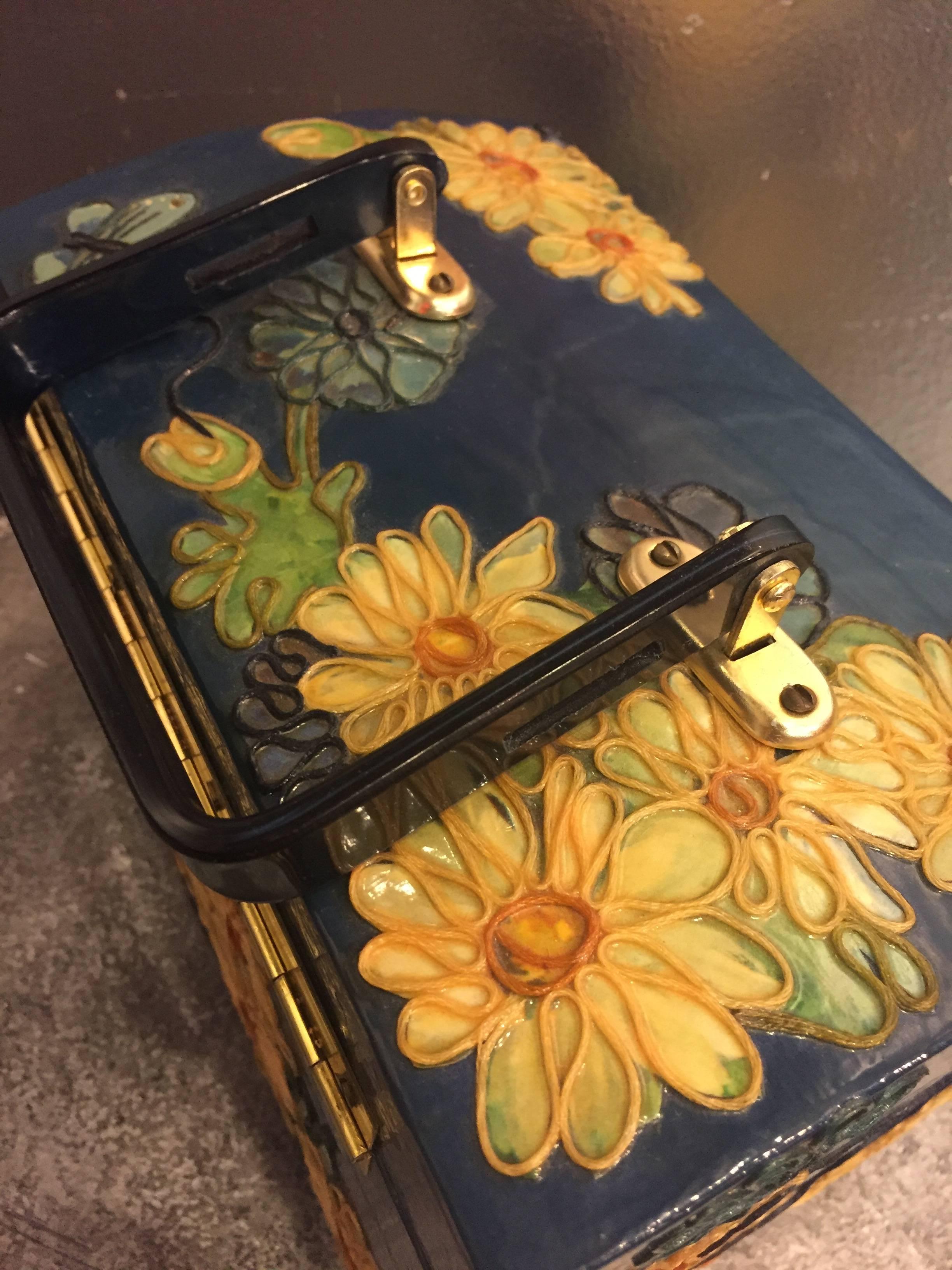 A fun 1960s wooden box purse with lucite handle, painted and applied fabric in a butterfly and floral pattern.  Trimmed with epoxy-ed on embroidery floss.  Interior is velvet lined with more decorative trim and mirror in lid. 