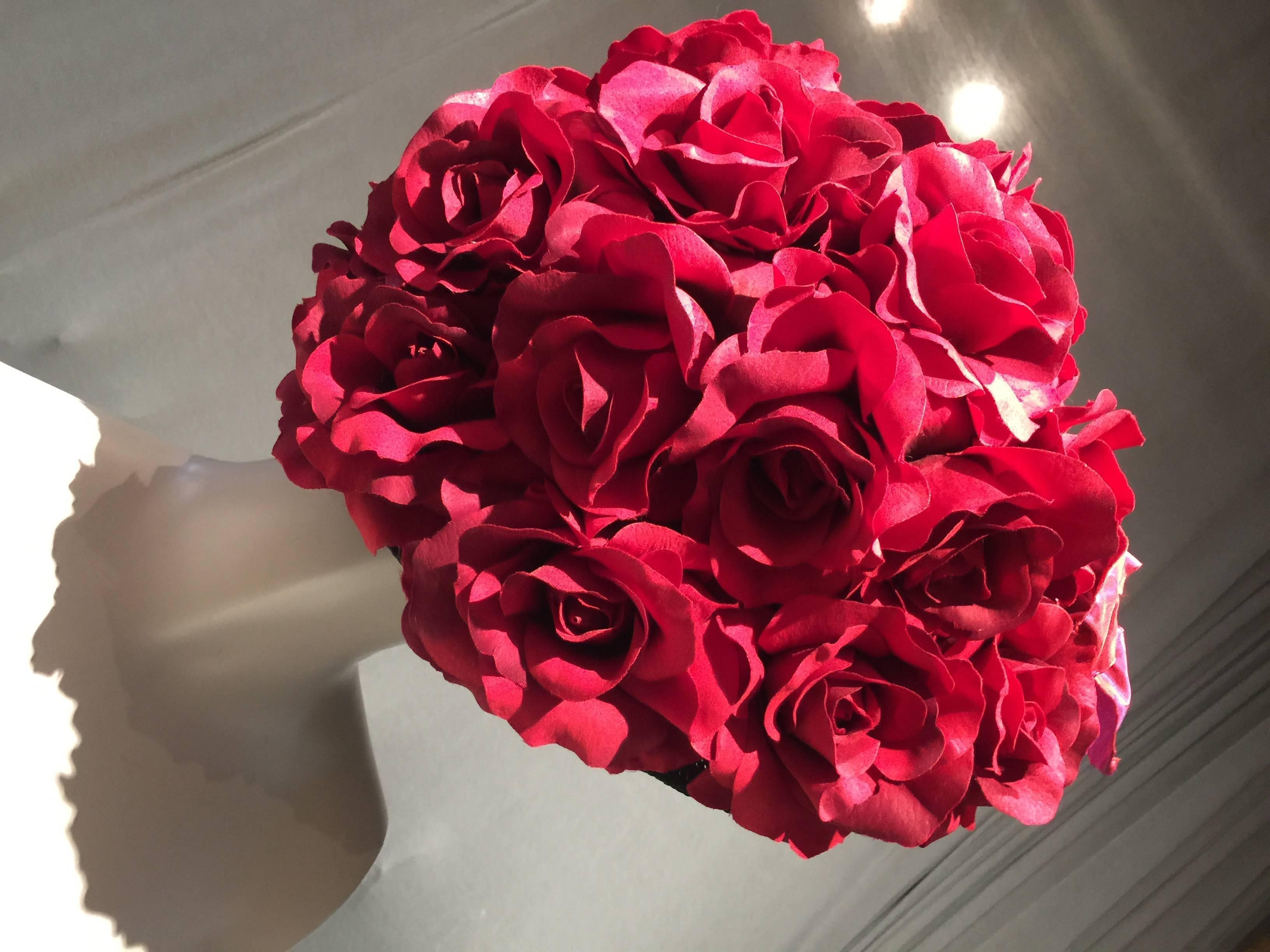 A wonderfully extravagant 1980s English straw flowerpot shaped hat in black covered entirely in red silk roses!  Originally sold at Saks Fifth Avenue. Medium size.