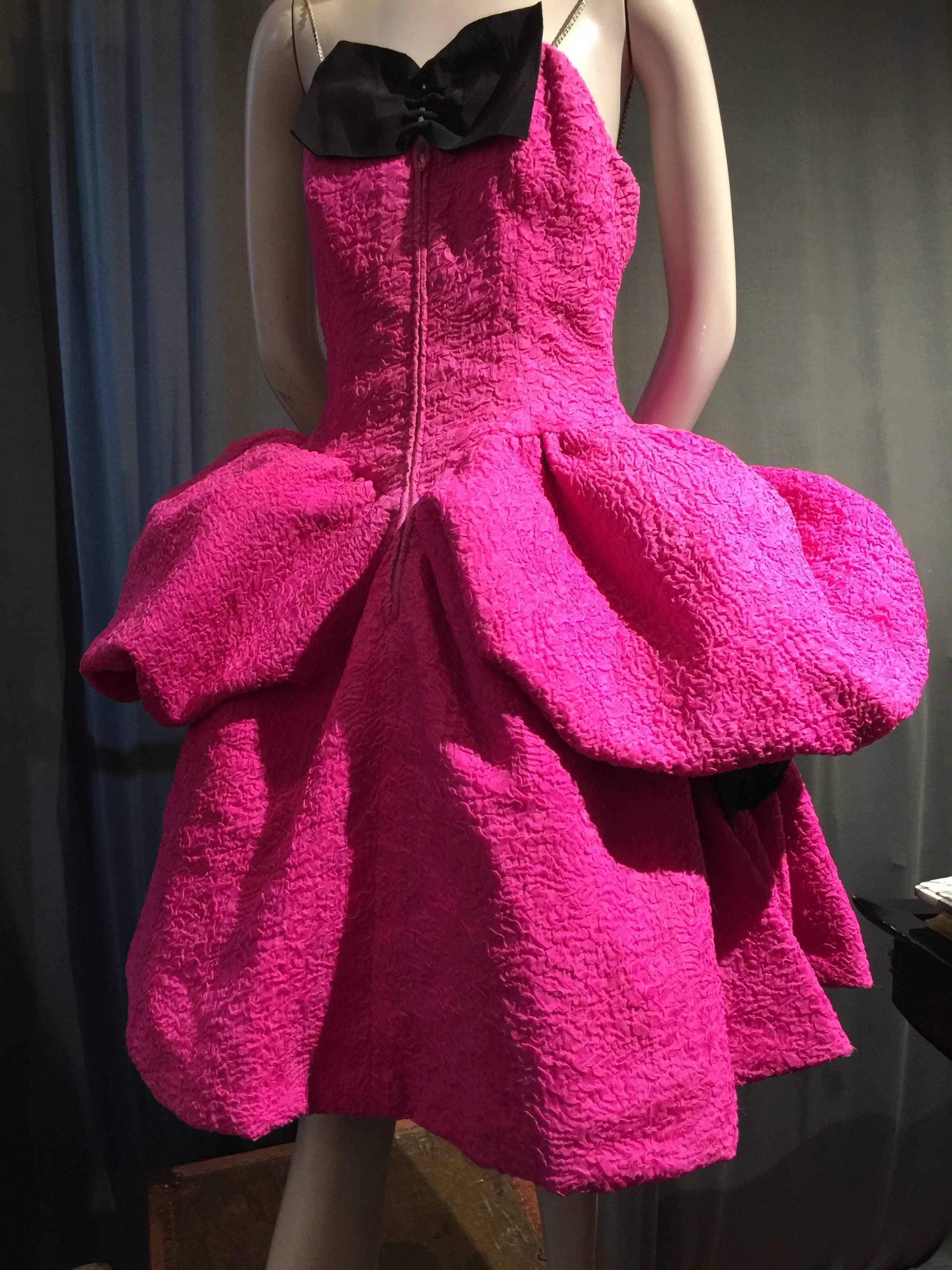 A fabulously sassy 1980s iconic Christian Lacroix design!  Hot pink textured silk spaghetti strap cocktail dress with full knee-length skirt, crinoline and horsehair underpinnings and two side poufs gathered into velvet ribbon bows. Front center