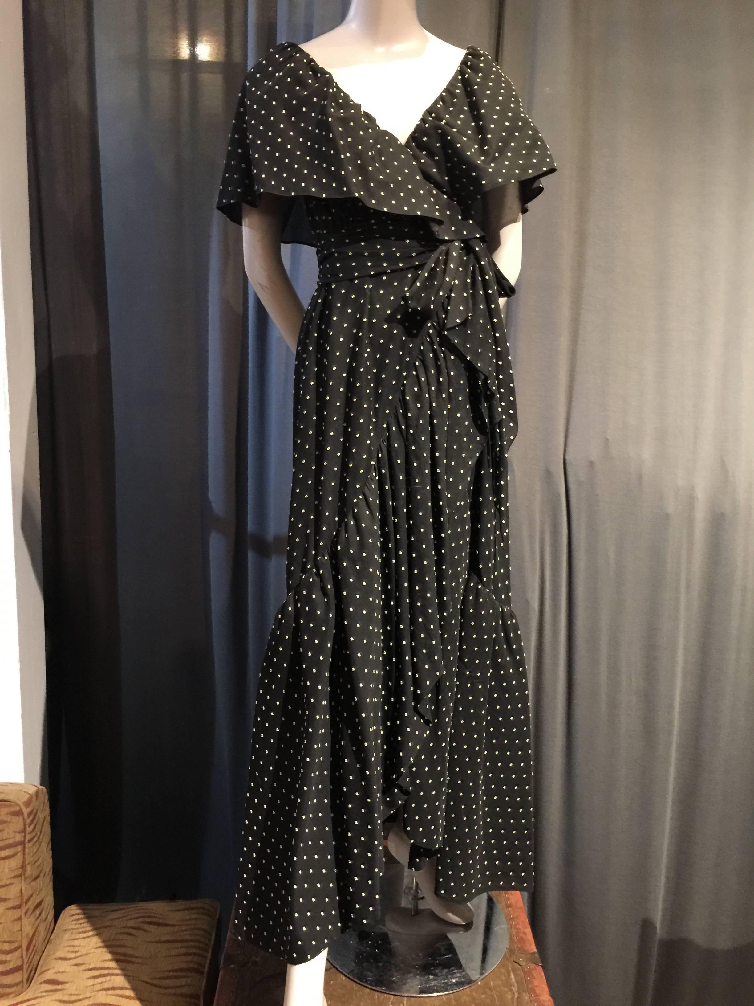 A gorgeous, soft and flattering 1970s Halston black cotton voile wrap maxi dress with a woven-in dot pattern throughout: Deep ruffled portrait decolletage with a hook closure at inner waist and an attached tie at outside.  Hem is edged with a long