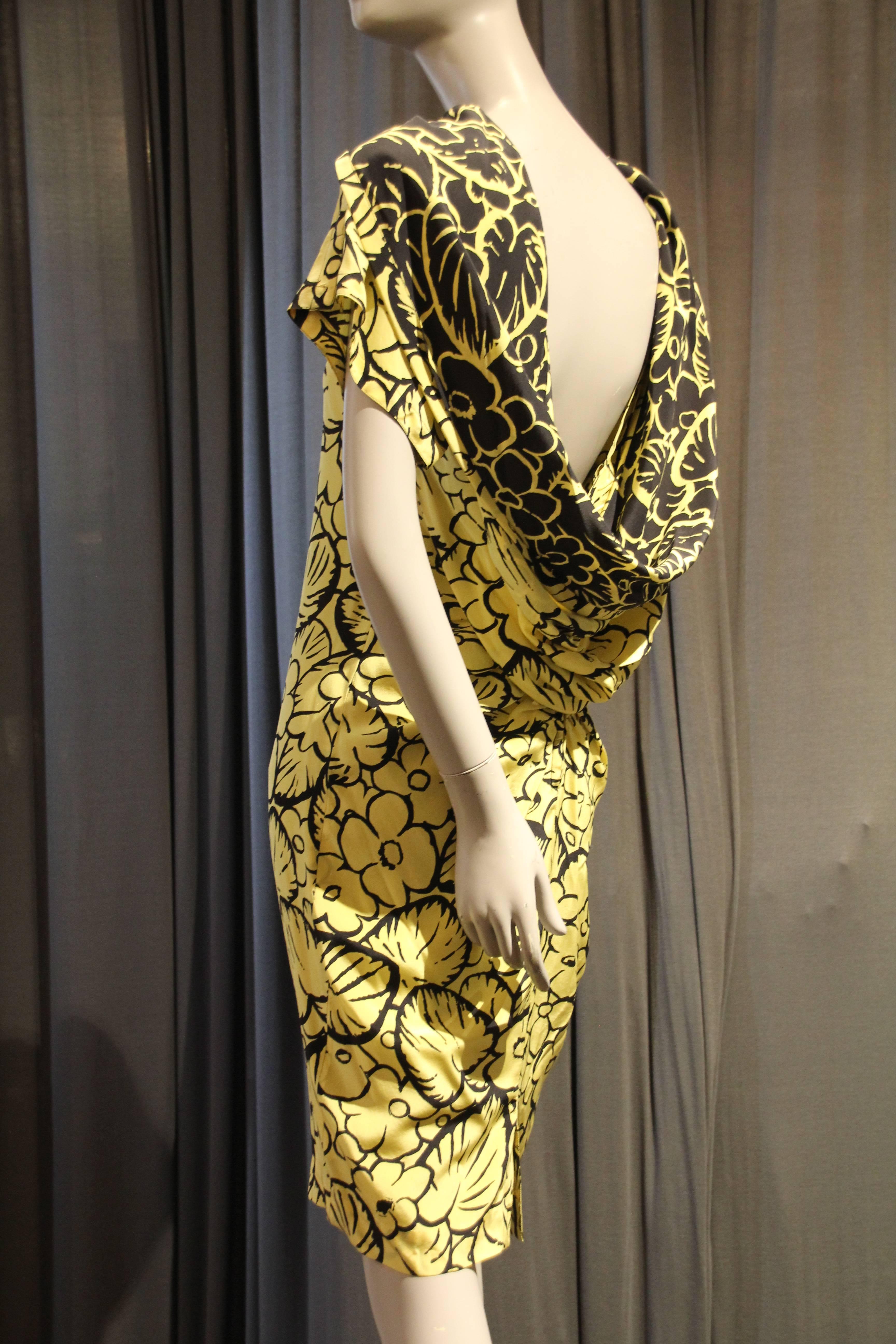 A sexy 1980s Gianni Versace silk cocktail dress in a yellow and black 1940s-inspired floral print.  A loose chemise fit with a slightly pegged hem and a reverse-printed, dramatically draped back collar. Bold shoulder pads. 