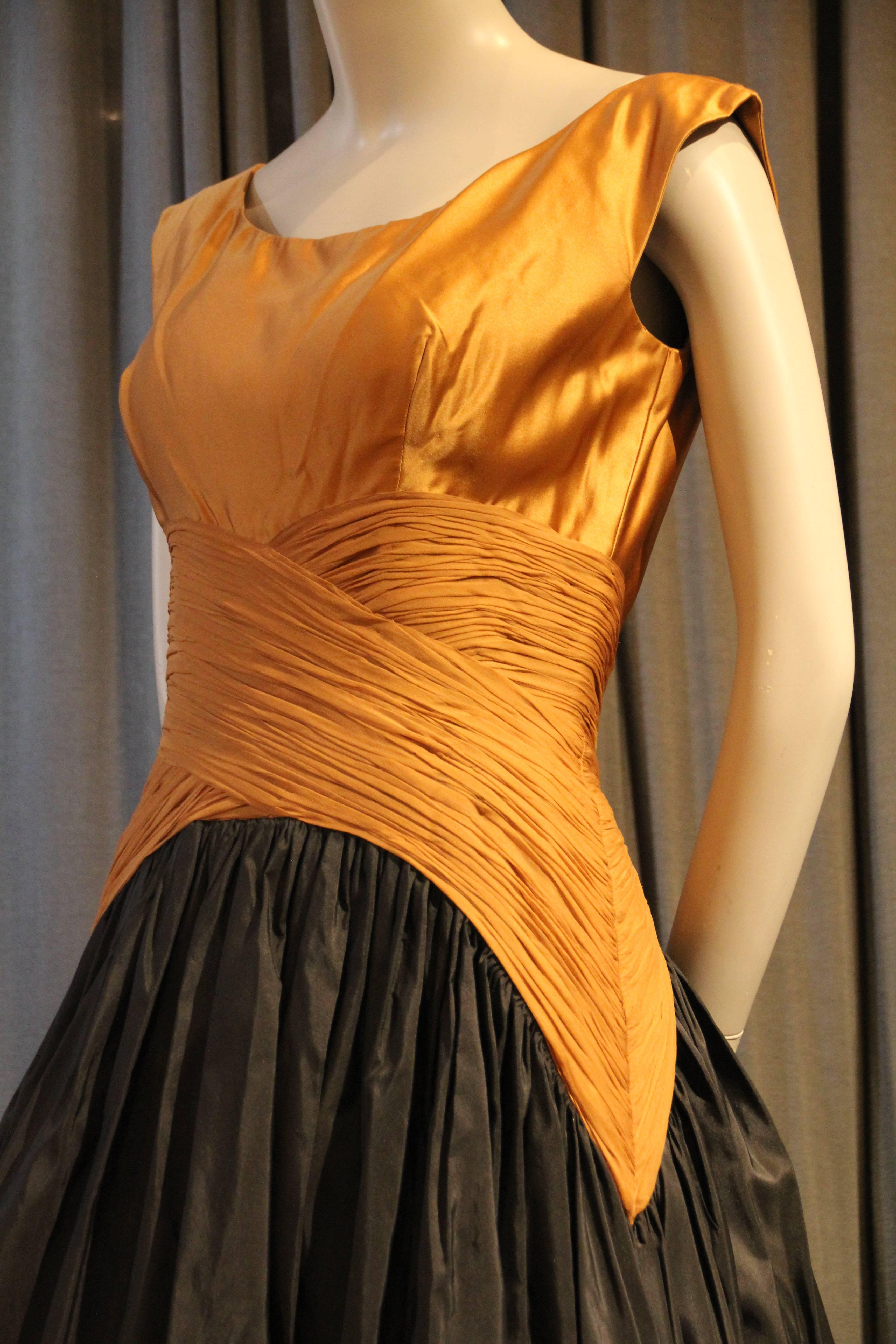 A beautiful 1950s Samuel Winston cocktail dress with full black taffeta skirt and exquisite bodice detailing in gold silk satin and ruched chiffon.Back zipper and organza and horsehair underskirt. 