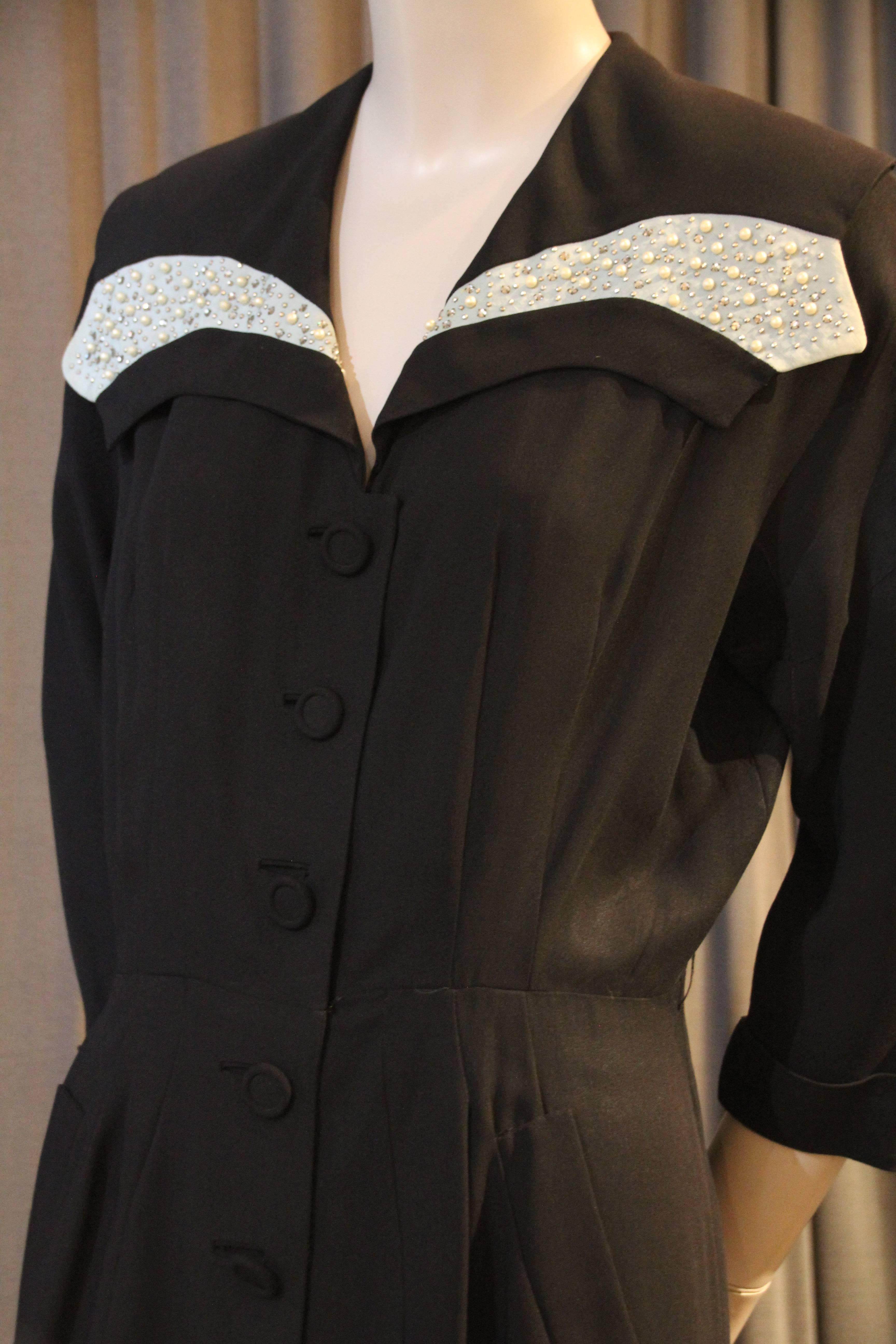 A beautiful late 1940s Fred A. Block Original black rayon crepe shirtwaist-style cocktail dress with fitted waist (belt missing) and covered buttons down front to hip.  Skirt is pleated and flowing with mid-calf original hem.  A beautiful collar is