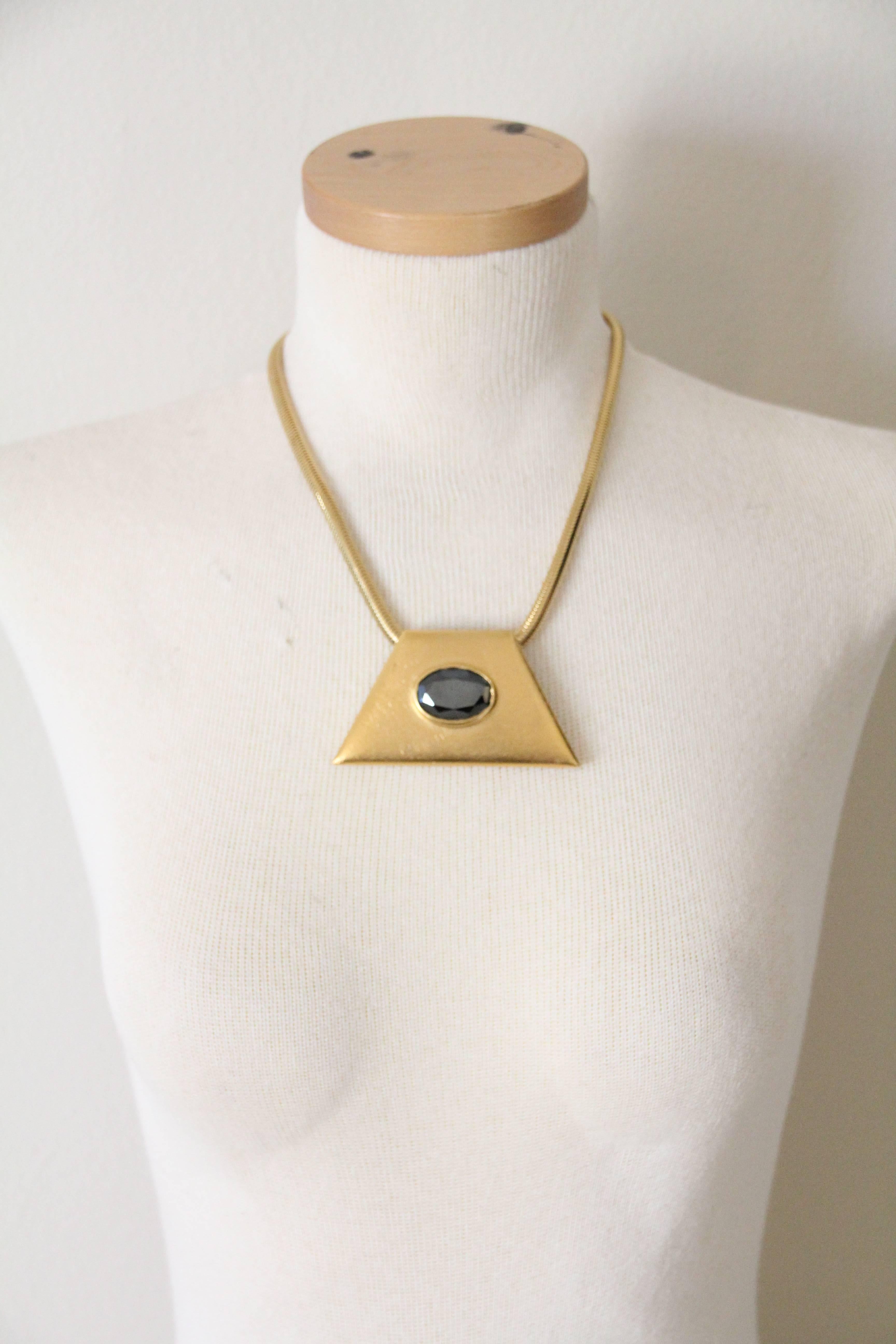 A bold 1980s YSL Egyptian-inspired brushed gold-tone trapezoid pendant with a central faceted hematite.  Pendant is on the original serpentine chain.  Chain measures 18