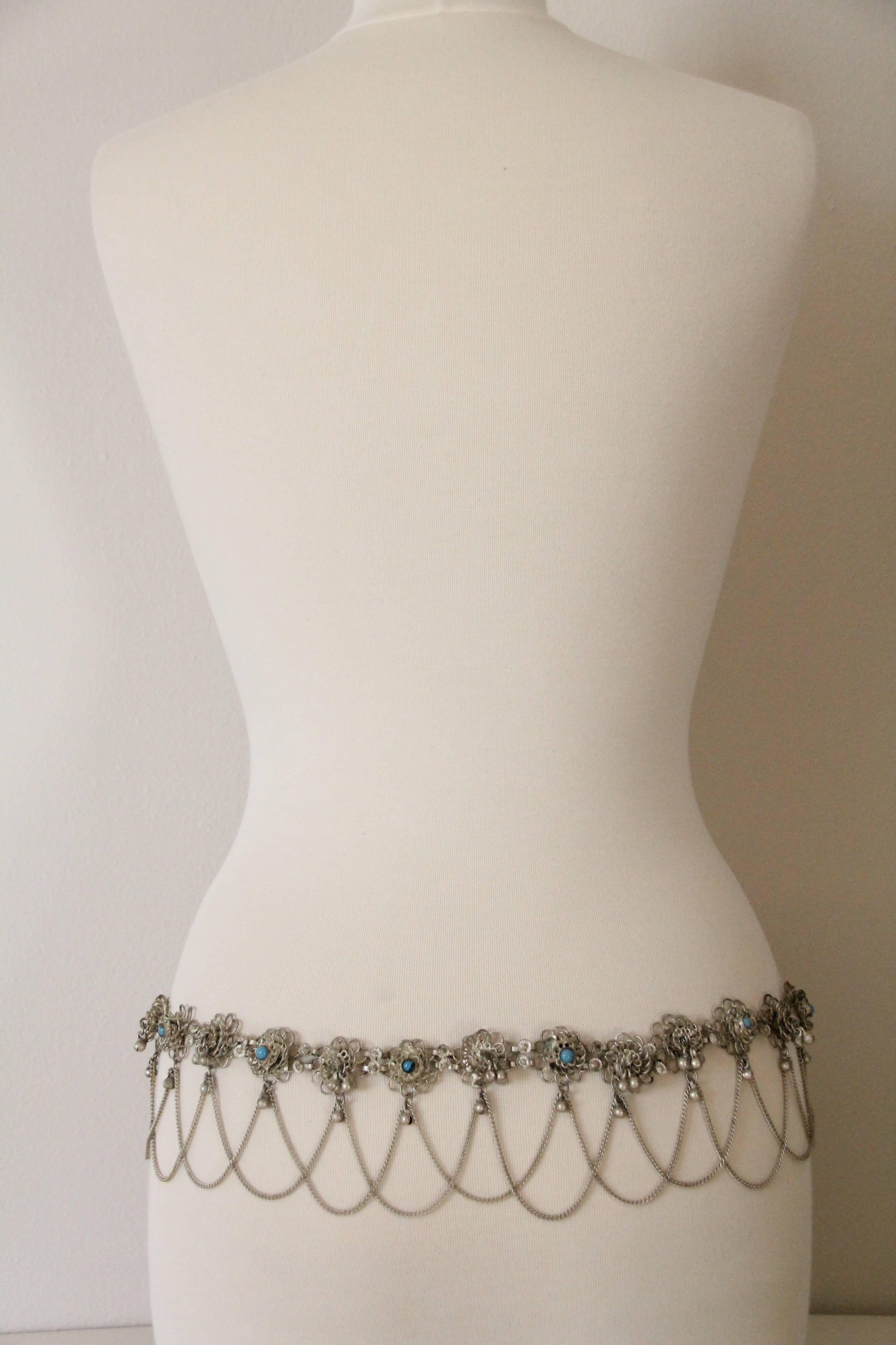 A beautiful 1970s coin silver Indian filigree chain belt with faux turquoise accents, chain swags and large center accent piece.  Hook closure. 

Adjustable size and will fit up to a 35