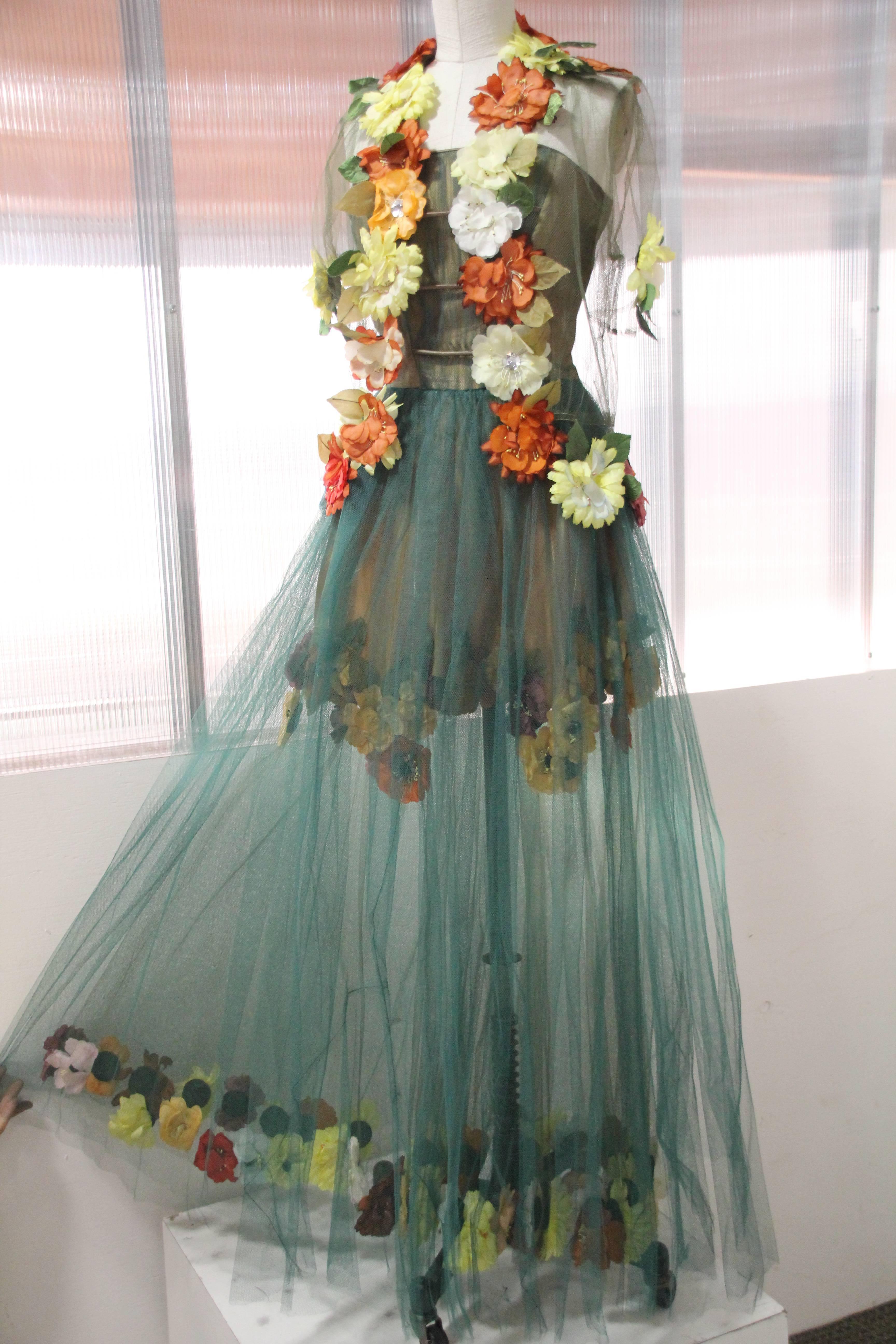 1950s 2-piece ensemble in moss green tulle with multi-color silk flower appliques backed in leather.  Strapless, ball gown with side zipper has short underskirt trimmed in flowers, veiled by outer long skirt which is hemmed in the same flowers.