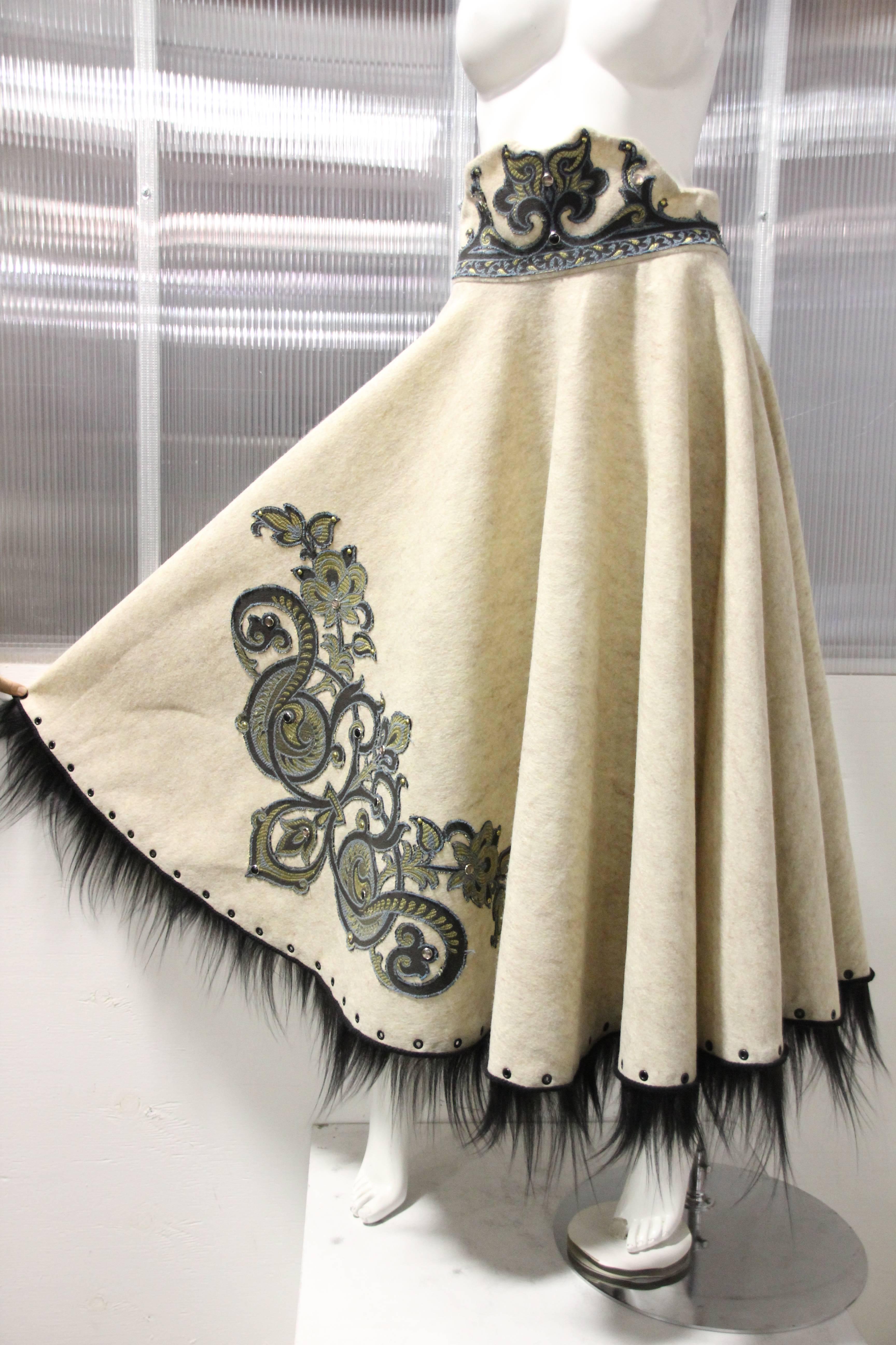 A custom-made ecru wool felt circle skirt in a 50's-style cut with decorative high waistband.  Embellished at waist and skirt with scroll-work applique and grommets.  Hem is trimmed in black wispy fur and grommets. Zippered in back.  