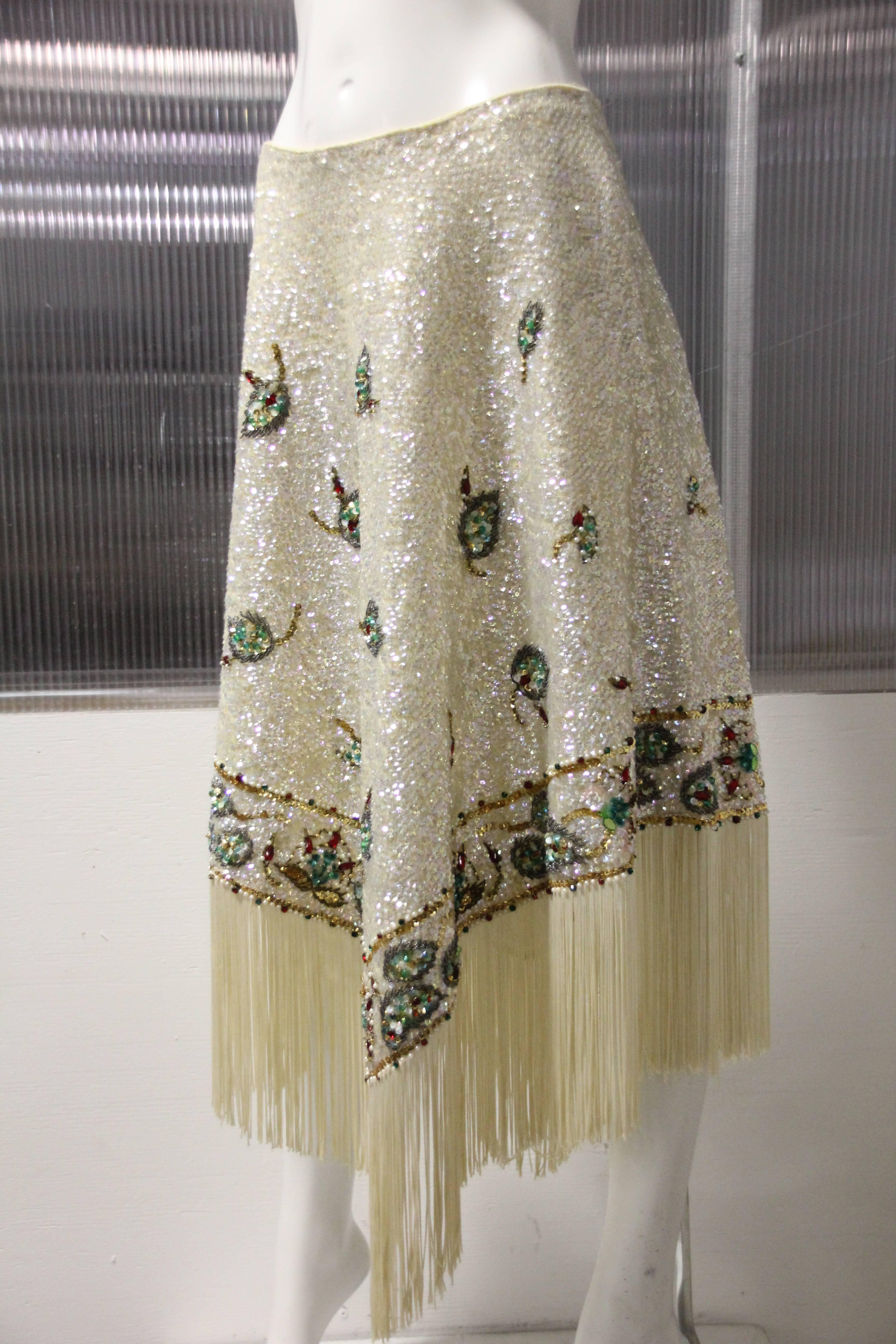 1960's Valentina Ltd. of Honk Kong soft cream wool knit beaded and sequin skirt is pointed at hem and trimmed with 8 inch cream rayon fringe.
Entire skirt is of iridescent sequins and multi colored beads and red glass stones creating a floral leaf