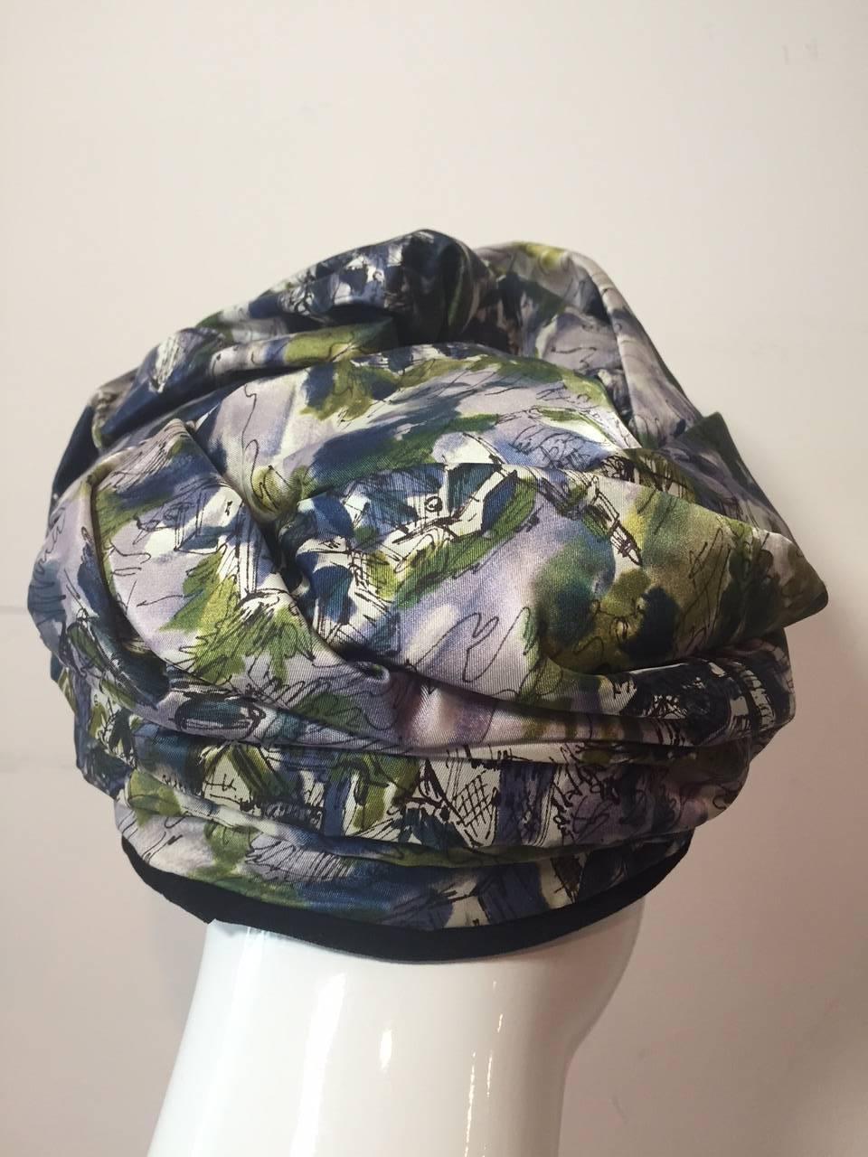 A gorgeous 1950s abstract floral printed silk in slate blues and green wrapped and gathered into an elegant top knot in turban style. Hat band is in black velvet.