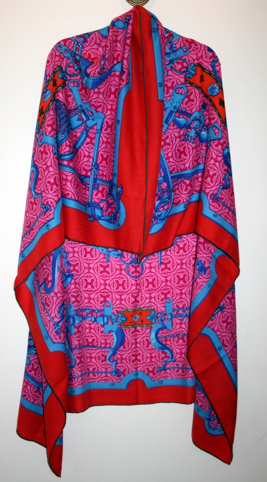 Never worn with the tag still attached, this Hermès Pink Mors et Gourmettes Remix Cashmere and Silk GM Shawl is a beautiful collectible.  The Henri d’Origney design features a variety of blue bits and chains on a vivid pink and red background of
