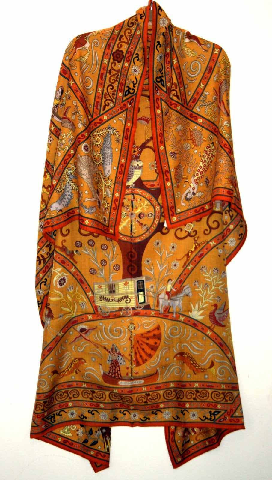 Pristine and never worn, this Hermès Saffron Peuple du Vent Cashmere and Silk GM Shawl still has the tag attached.    The Christine Henry design features an intriguing assortment of bohemian musicians, performers and animals on a golden mustard
