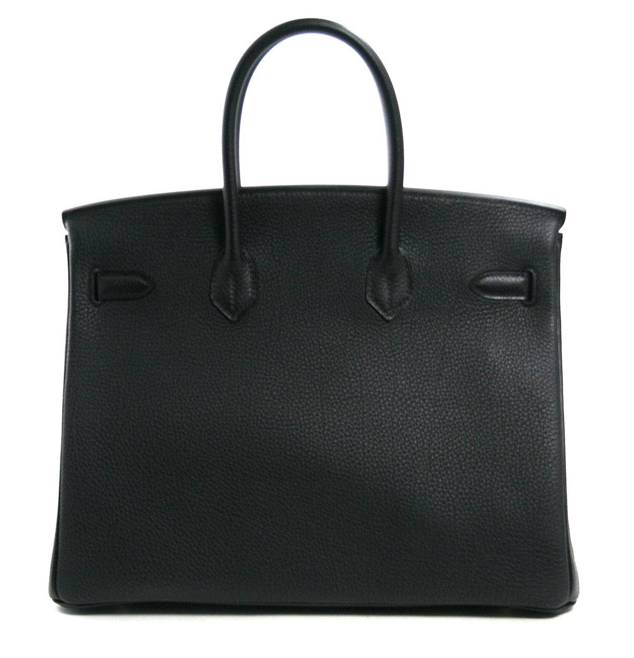 Never before carried, this Hermès Black 40 cm Togo Leather Birkin still has the plastic intact on the hardware.     Considered the ultimate luxury item the world over and hand stitched by skilled craftsmen, wait lists for the Birkin often exceed a