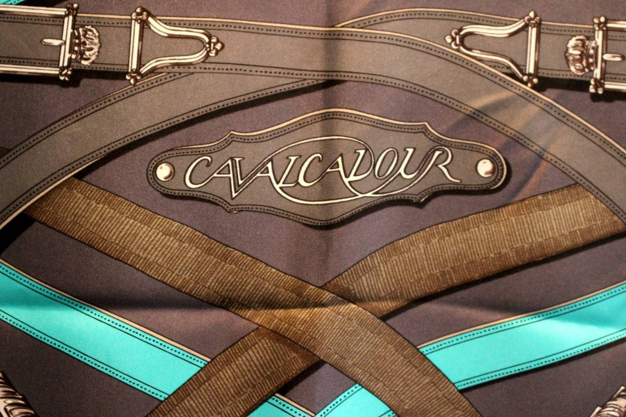 Worn once, this Hermès Black Cavalcadour Silk Scarf is in mint condition; a great find for a savvy shopper.  Designed by Henri d’Origny, the classic print artfully displays equestrian harnesses, buckles and belts in a symmetrical swirling design.   