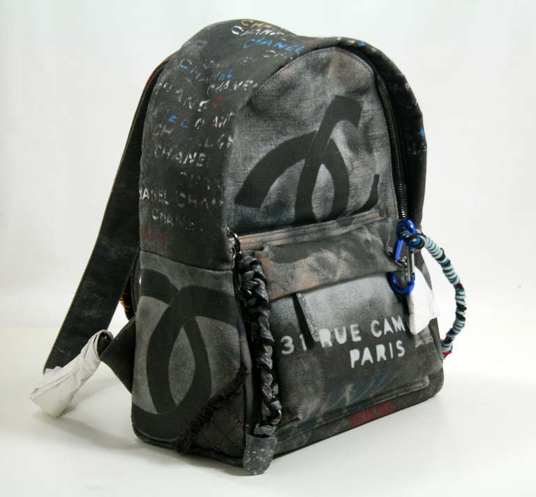 Chanel’s Black Graffiti Art School Backpack is a former store display in pristine unworn condition.  The tag and protective paper wrappings have been removed but this item has never been carried.   The completely sold out style is from the 2014