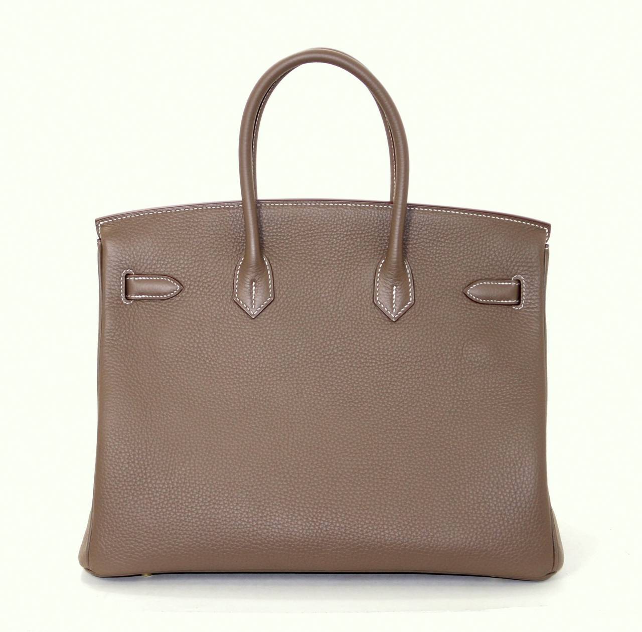 Pristine, store fresh condition (plastic on hardware) Hermès Birkin Bag in Etoupe (TAUPE) Clemence Leather with Gold Hardware, 35 cm size.   
Crafted by hand and considered by many as the epitome of luxury items, Birkins are extremely difficult to