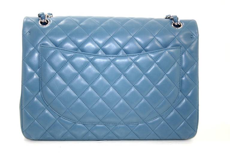 Chanel’s Blue Lambskin Maxi is in pristine unworn condition.   The largest version of the double flap style, it is rarely seen in this serene shade of blue; a must have for any collection.
Blue lambskin is quilted in signature Chanel diamond