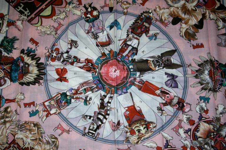 Pristine and unworn, this striking Hermès Pink Kachinas Cashmere and Silk GM Shawl is a beautiful and collectible design.  Created by Kermit Oliver, the only American artist to design for Hermès, it features a variety of Native American masked