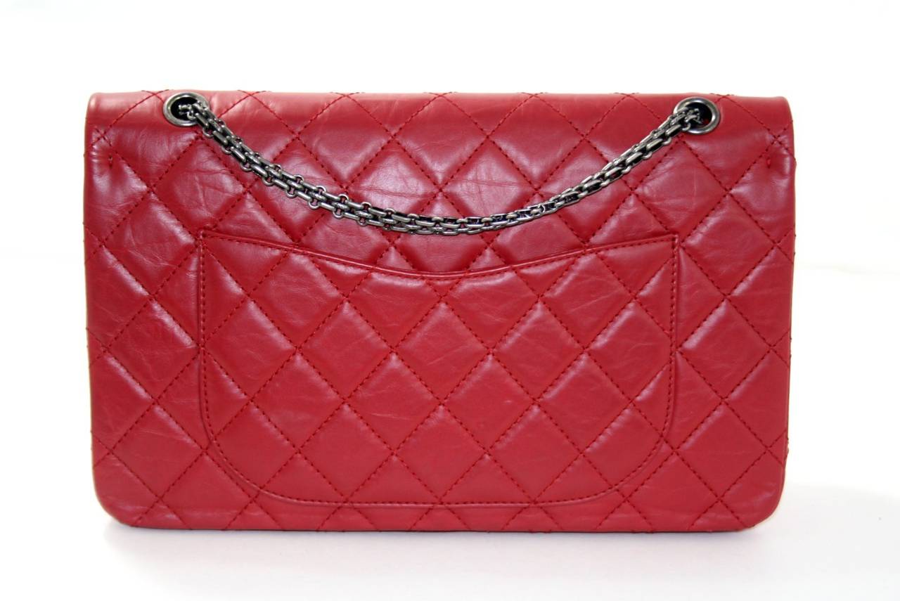 Pristine and never carried, this Red Lambskin 255 Reissue from Chanel is a store return.   The dazzling updated version of the classic is in the largest size of the reissues with a retail price of over $6,000.00 with taxes.    
Red distressed