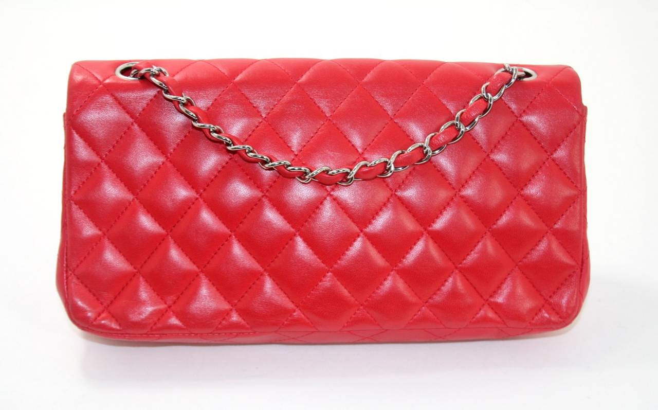 Chanel’s Red Lambskin East West Flap Bag is a beautiful addition to any collection.  It is in pristine condition.  The small classic style is elegant and sophisticated;  perfect for day or evening year round.    
Lipstick red lambskin is quilted in