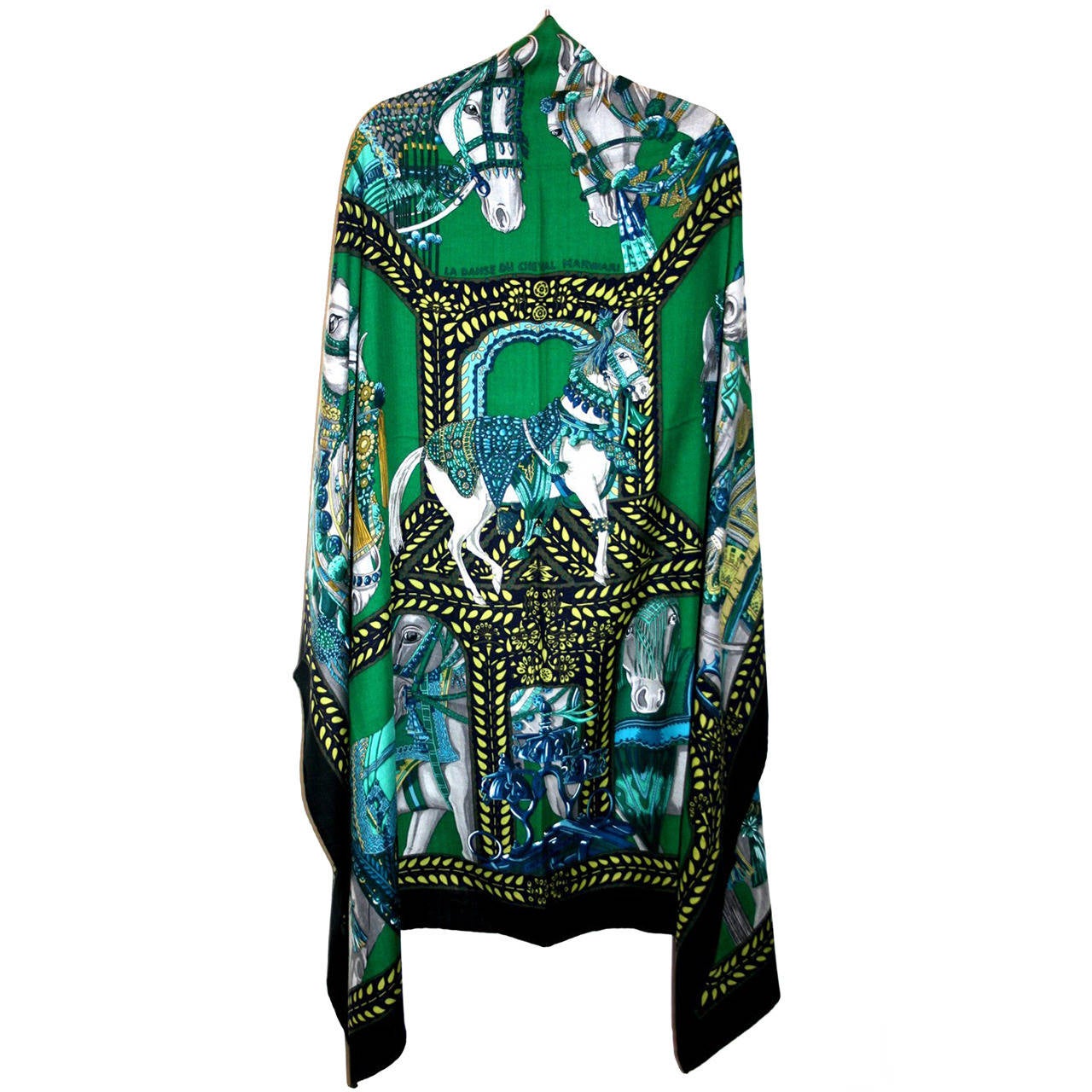 Never worn, this Hermès La Danse Du Cheval Marwari Cashmere and Silk Green GM Shawl is a highly coveted piece.  The Annie Faivre design features jewel adorned white regal steeds on a bright green background with black and turquoise accents.  It may