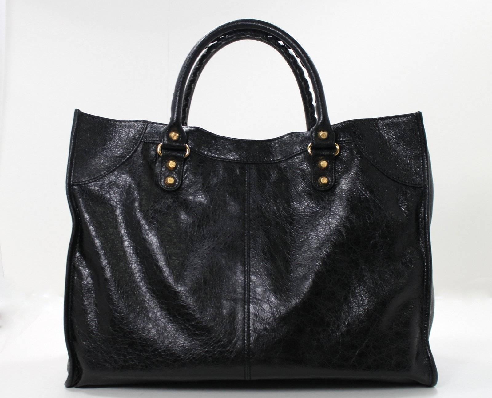 Balenciaga BLACK Lambskin Monday Bag with GIANT Gold Hardware- NEW; retail $2,095.00 plus taxes
The iconic Balenciaga silhouette is recreated each season in exciting colors and varied shapes.   The Monday Tote resembles a proportionally larger